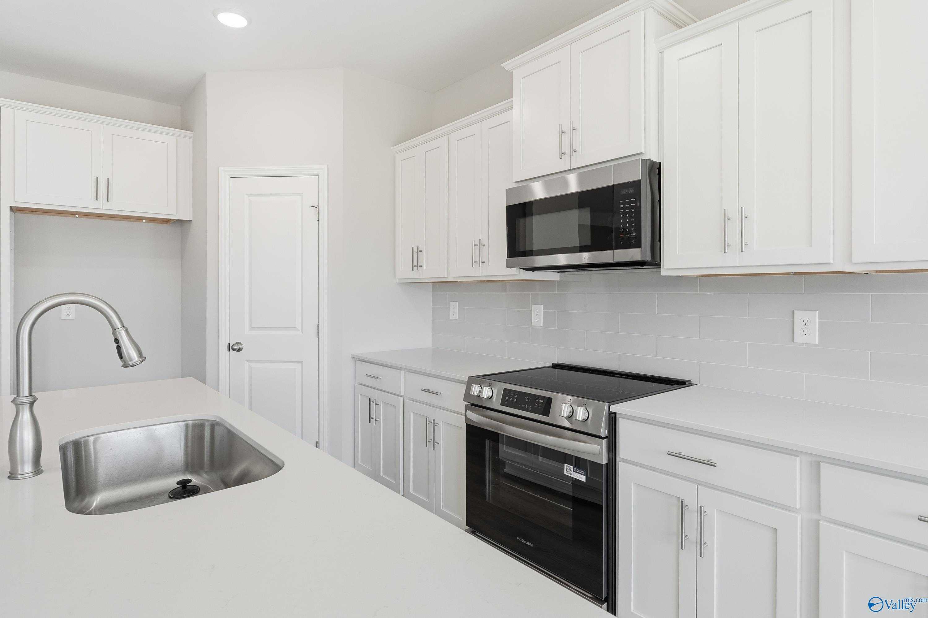 Modern white kitchen featuring stainless steel appliances, quartz counters, and subway tile backsplash in Davidson Homes The Montgomery B, Toney, AL