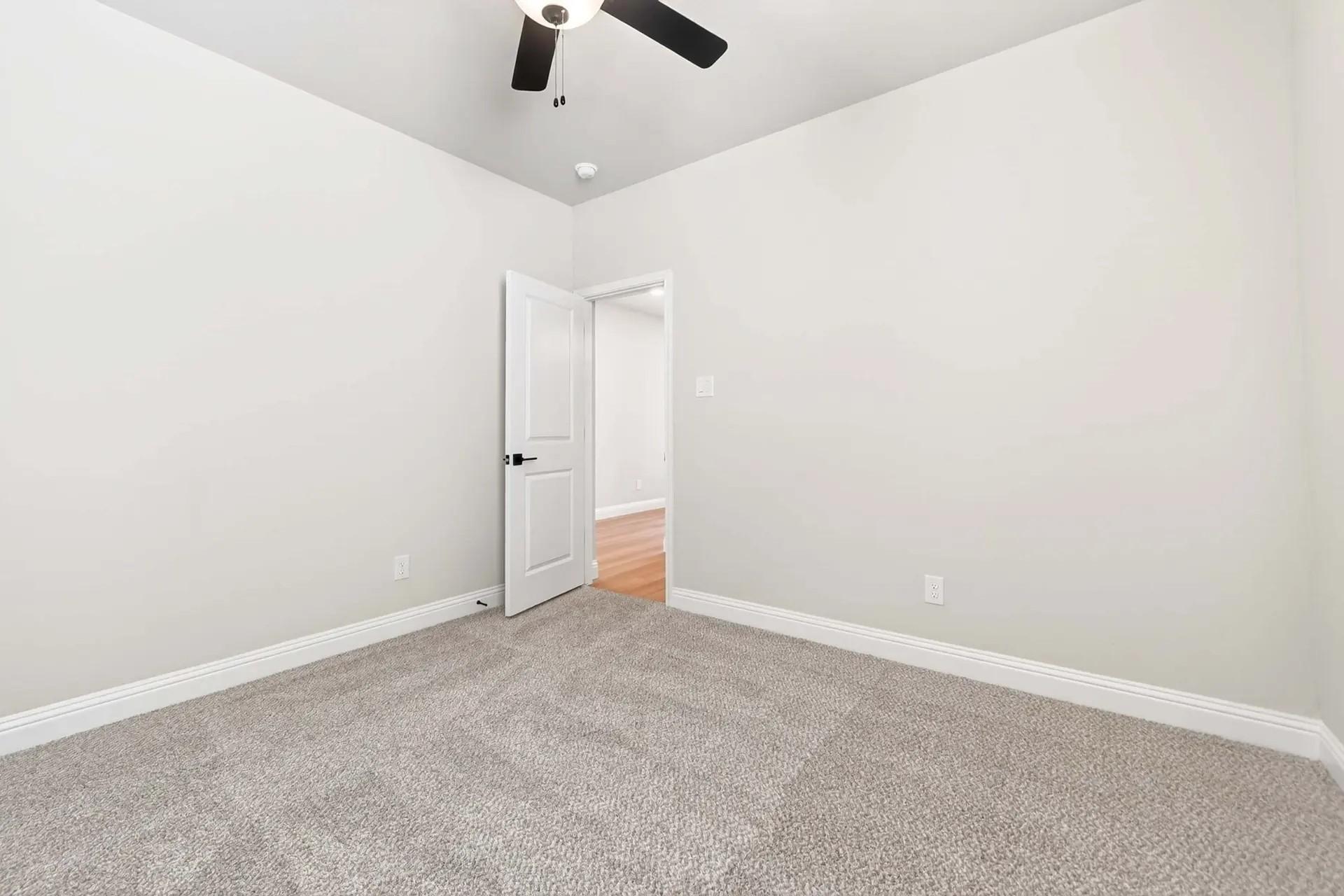 Spacious carpeted bedroom with ceiling fan in The Holly C floor plan by Davidson Homes in Heartland, Texas.