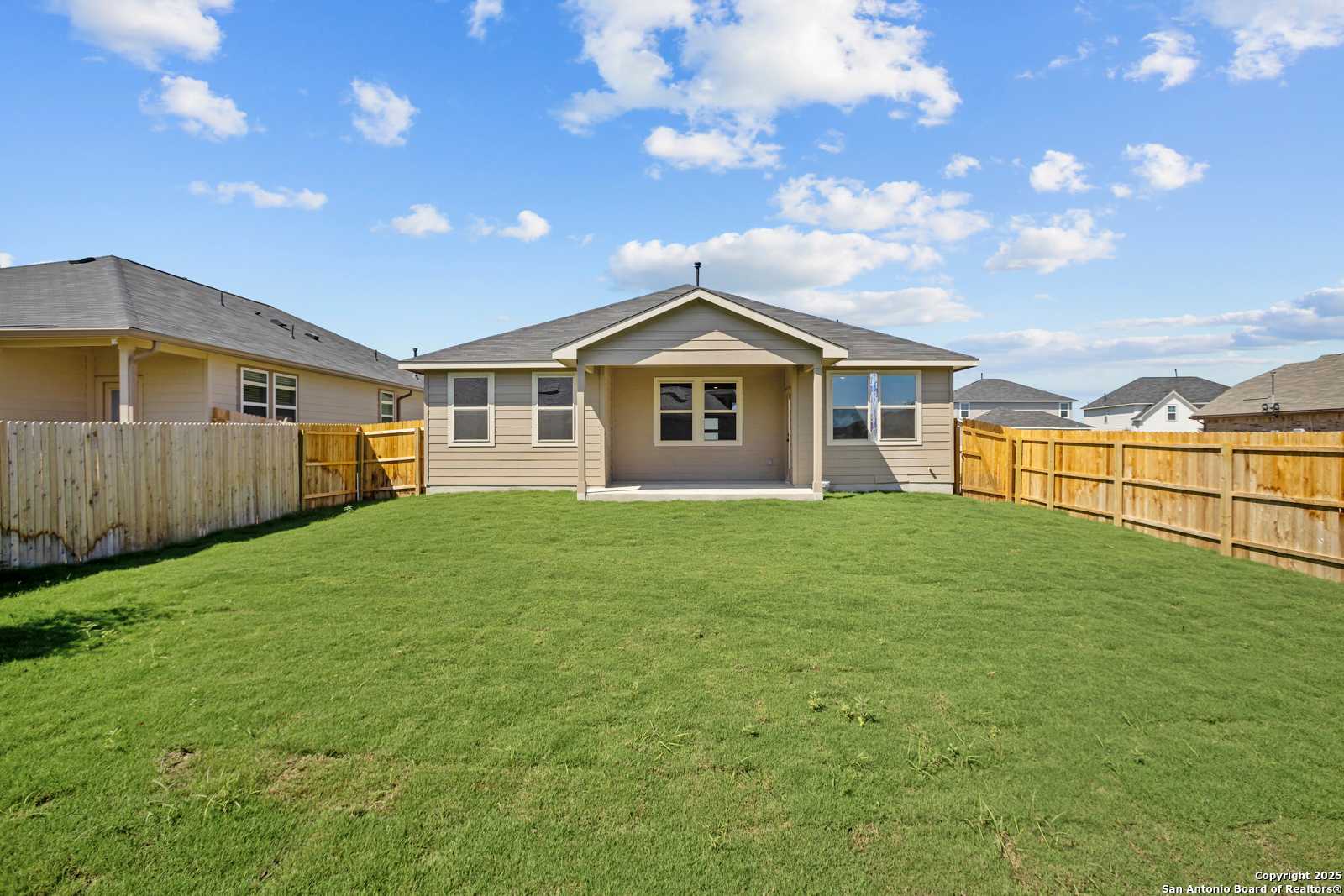 Private backyard with lush green lawn, wooden fence, and covered patio in Davidson Homes The Asheville E, Converse, Texas