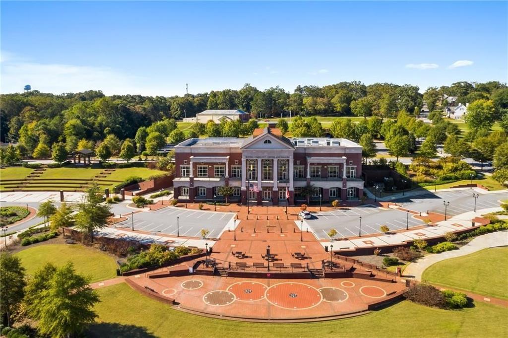 Aerial view of grand red brick Danbury E two-story home with columned entrance and lush green landscaping in Melody Lakeside Estates, Buford, Georgia