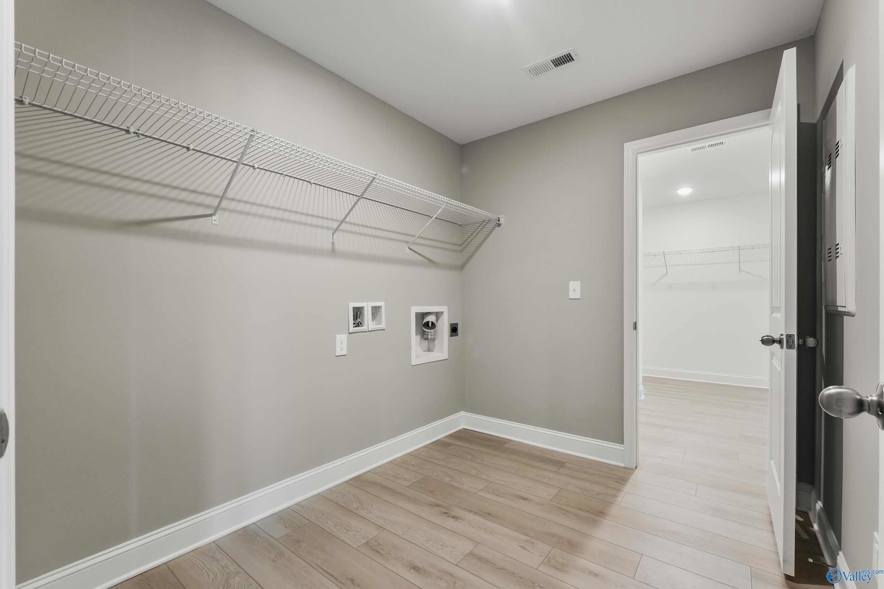 Spacious laundry room with wire shelving, washer-dryer hookups, and open doorway in The Everett B, Davidson Homes, Athens, Alabama