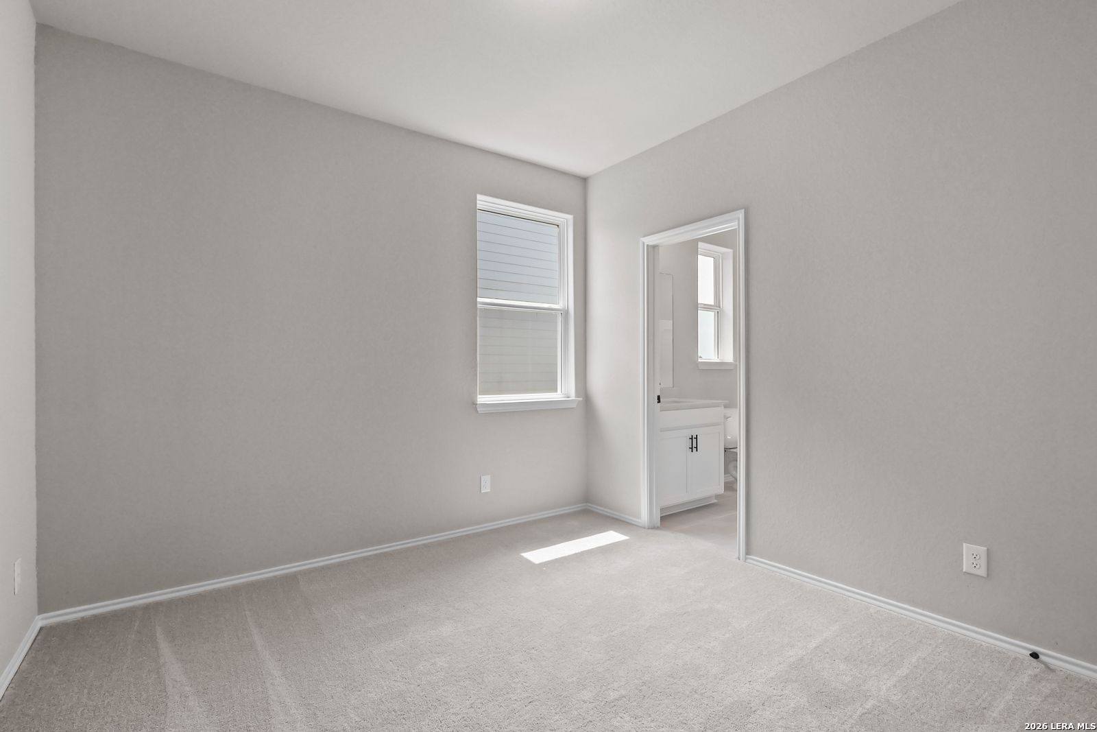 Bright bedroom with adjoining bathroom in The Daphne H floor plan at Hannah Heights, Seguin, Texas.