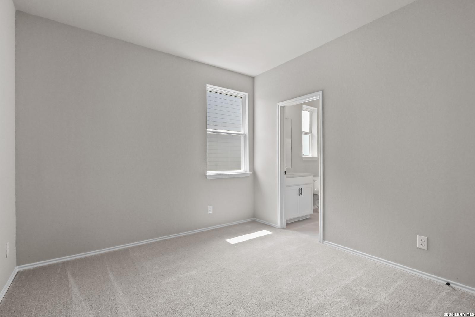 Bright bedroom with adjoining bathroom in The Daphne H floor plan at Hannah Heights, Seguin, Texas.