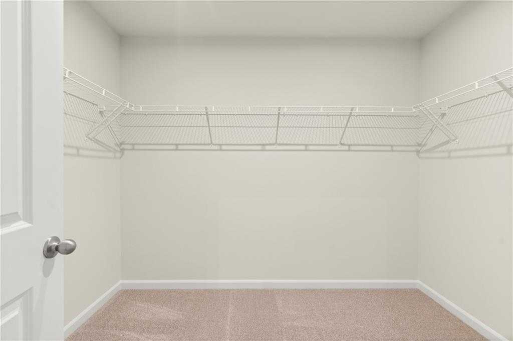 Spacious walk-in closet with wire shelving and beige carpet in Davidson Homes The Cary A, Kennesaw, Georgia