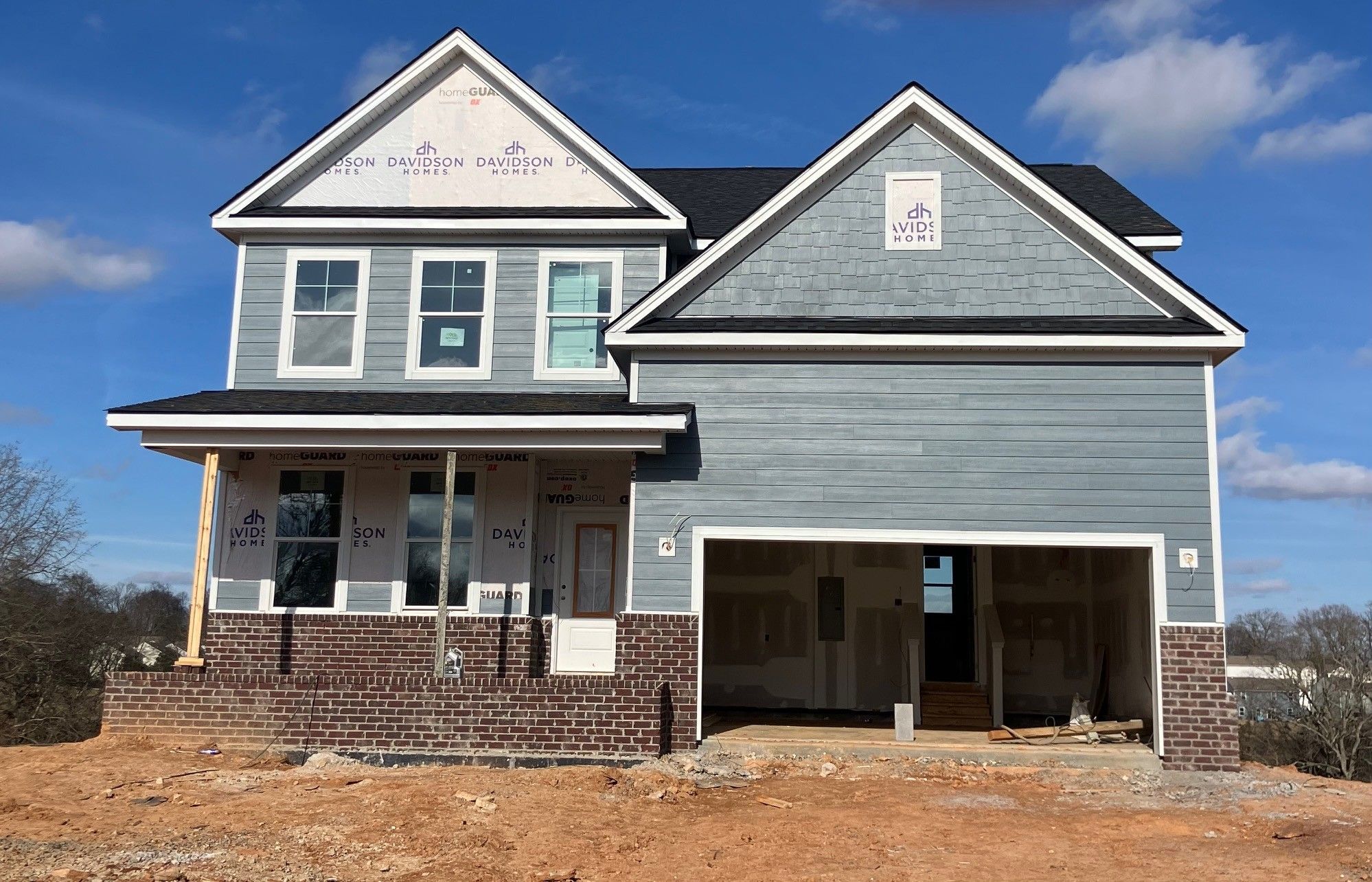Two-story blue home with front porch, two-car garage, and brick base under construction in Calista Farms, White House, Tennessee