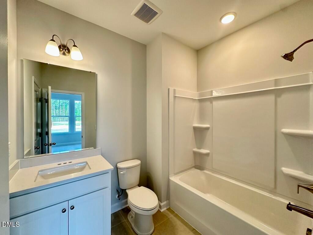 Bright bathroom featuring white quartz vanity, alcove tub shower, large mirror in Davidson Homes Mitchell 4-bedroom townhome, Knightdale NC