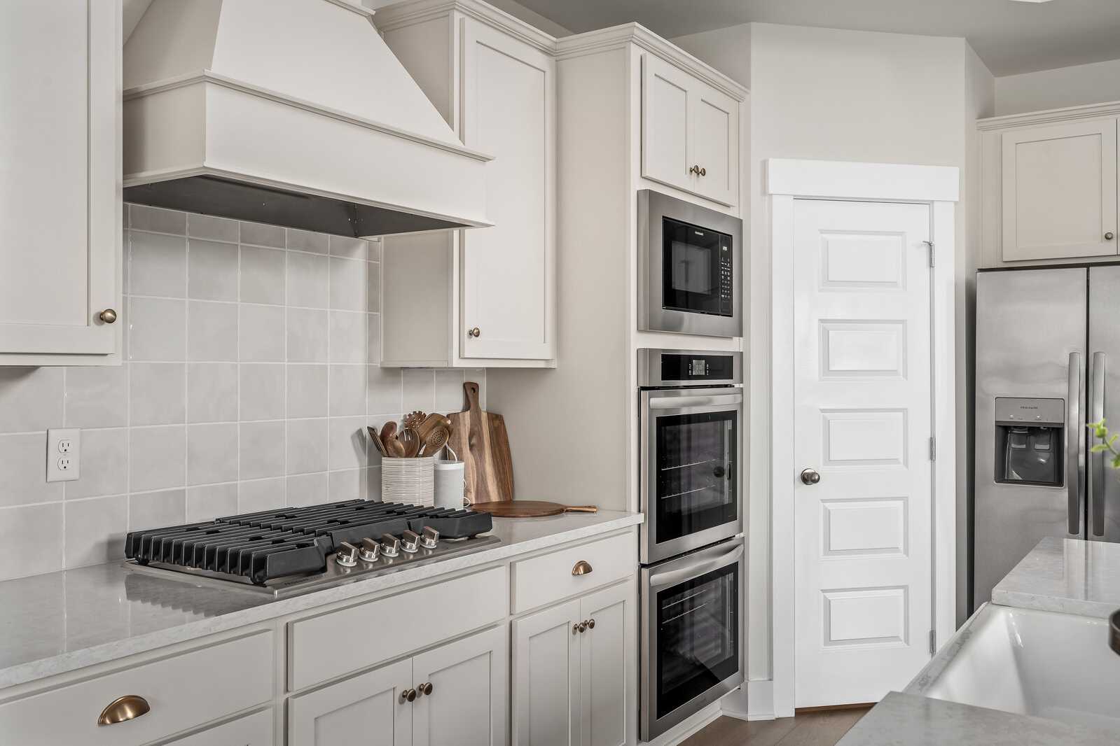 Modern kitchen in Woods Crossing, Gallatin TN by Davidson Homes with white cabinets, stainless double oven, gas range, subway tile