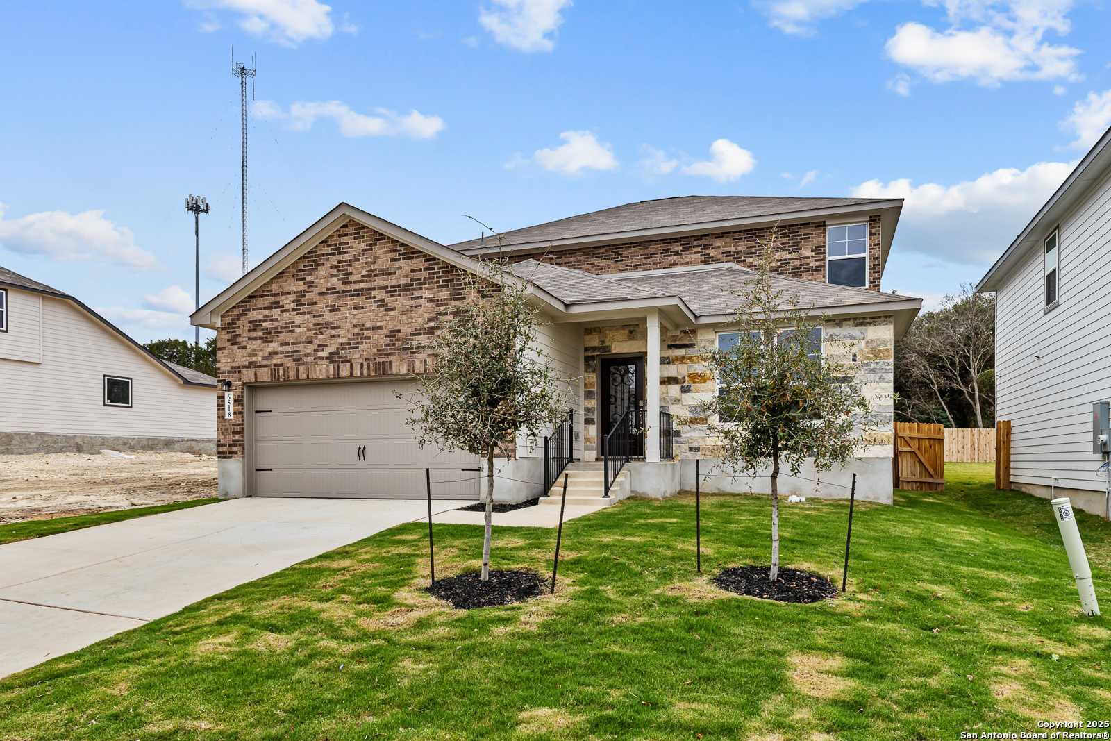 Two-story brick home with two-car garage, olive trees, and landscaped yard in Royal Crest, San Antonio, Texas