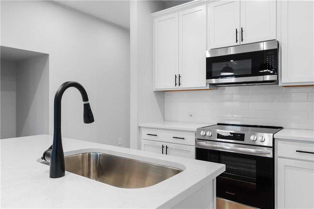 Modern white kitchen with stainless steel appliances, pull-down faucet, subway tile backsplash in Davidson Homes The Durant A, Emerson, GA