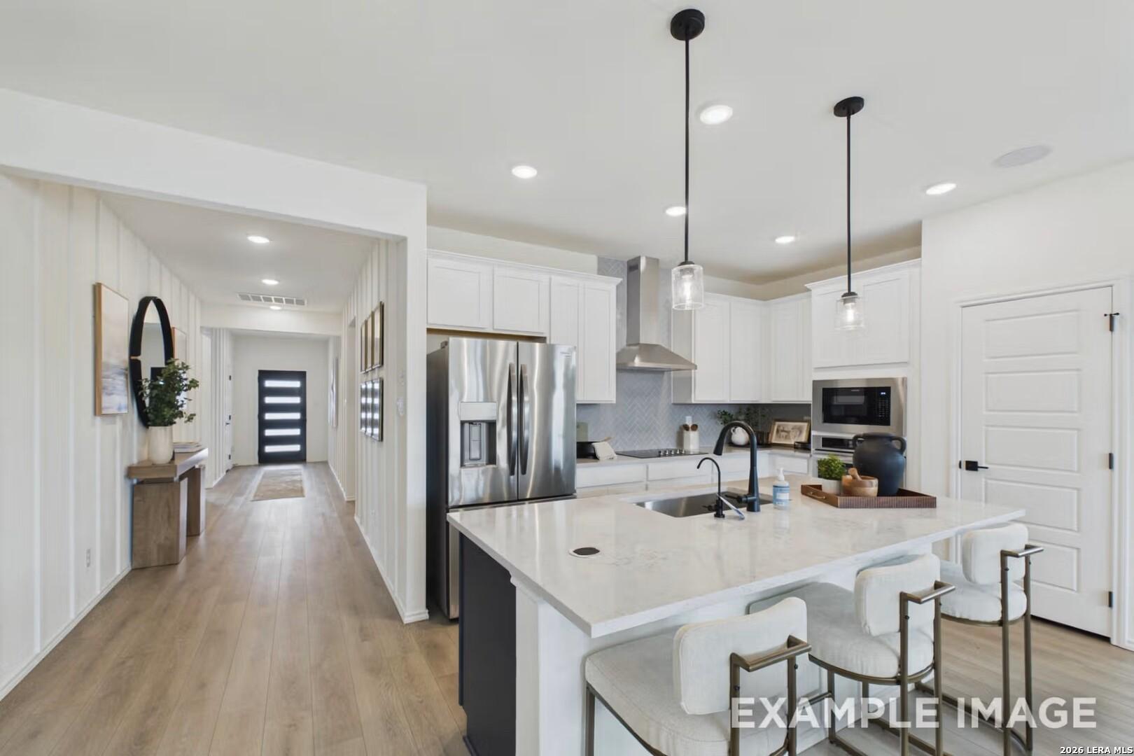 Modern kitchen with white cabinets, quartz island, and stainless steel appliances in The Laurel I home, Rayburn Valley, TX.