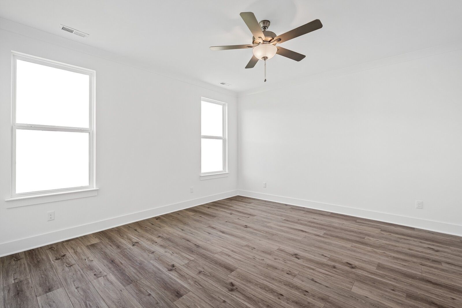 Bright secondary bedroom with ceiling fan, large windows, and hardwood floors in Davidson Homes The Hawkins, Murfreesboro, TN