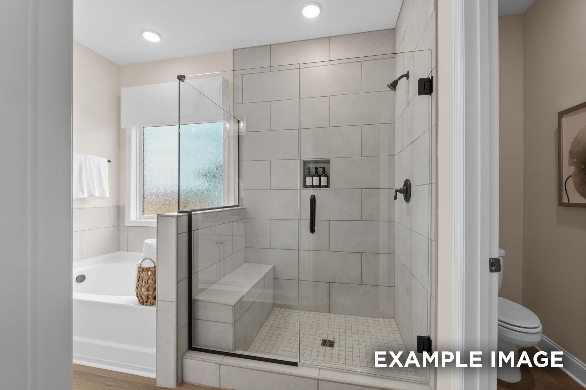 Spacious master bathroom in The Laurel N with frameless glass shower, soaking tub, and tiled accents