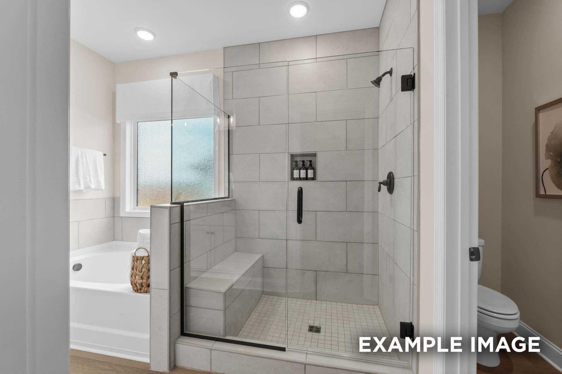 Spacious master bathroom in The Laurel N with frameless glass shower, soaking tub, and tiled accents