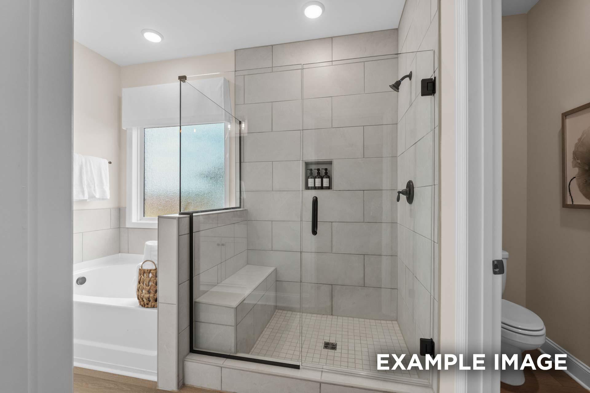 Luxurious master bathroom in The Laurel M featuring tiled walk-in shower, freestanding tub, and frosted glass window