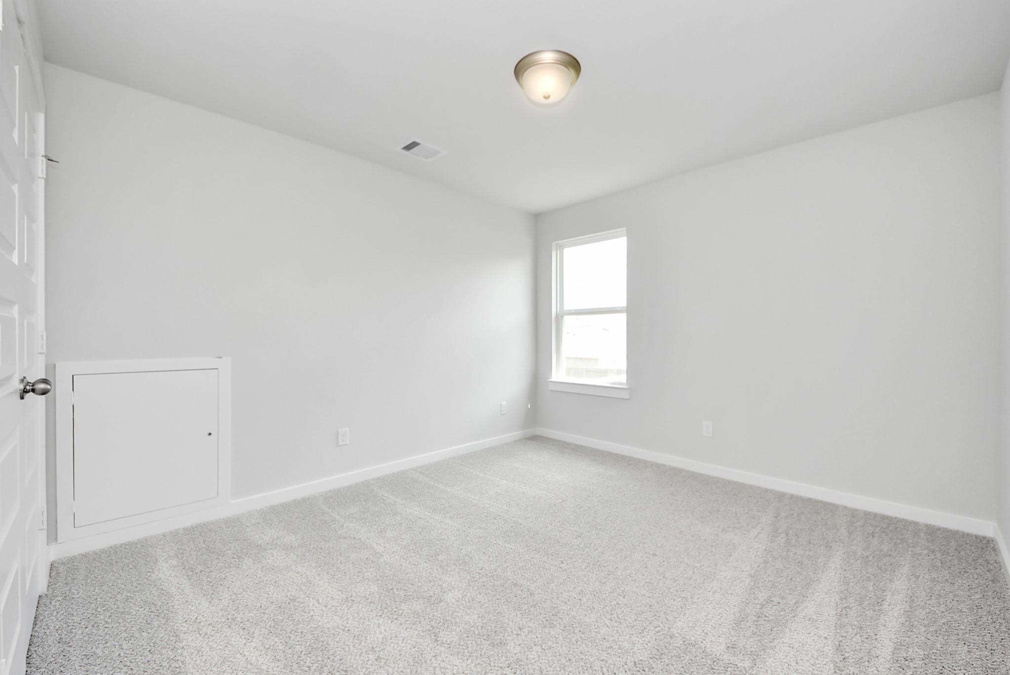 Bright, carpeted bedroom with white walls and storage access in The Verano B floor plan, Sunterra, Katy, Texas.