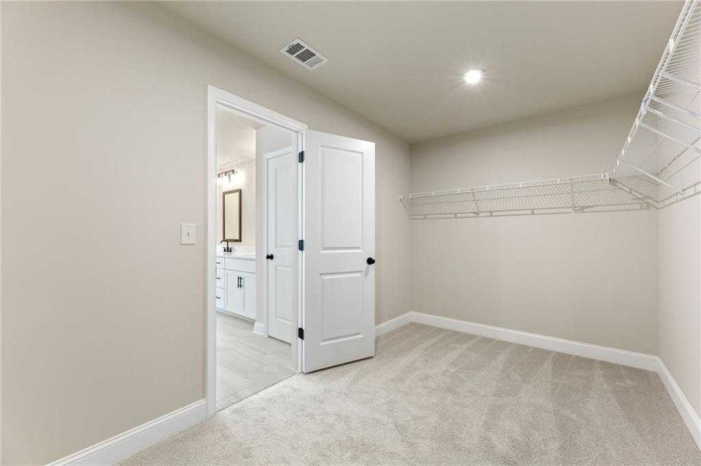 Spacious walk-in closet with white wire shelving, open to master bathroom with vanity in Davidson Homes The Hickory E, Buford, GA