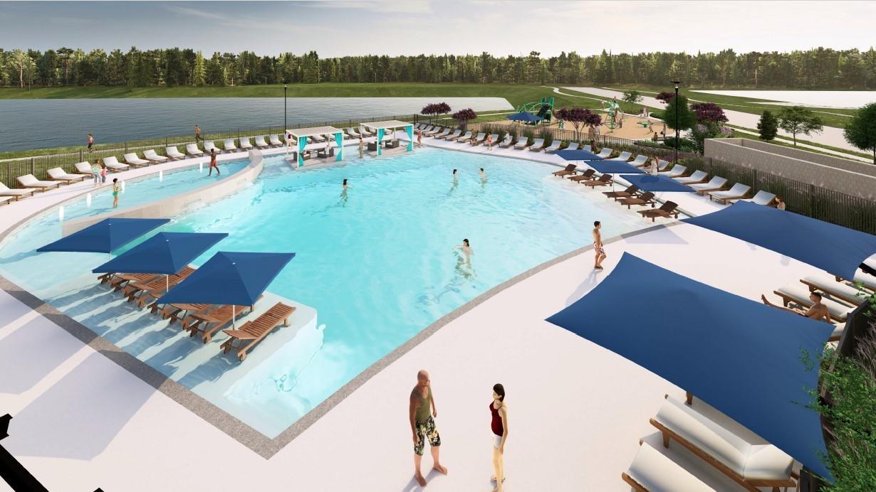 Resort-style community pool with shaded loungers and lake views at Sundance Cove, Davidson Homes community in Crosby, Texas