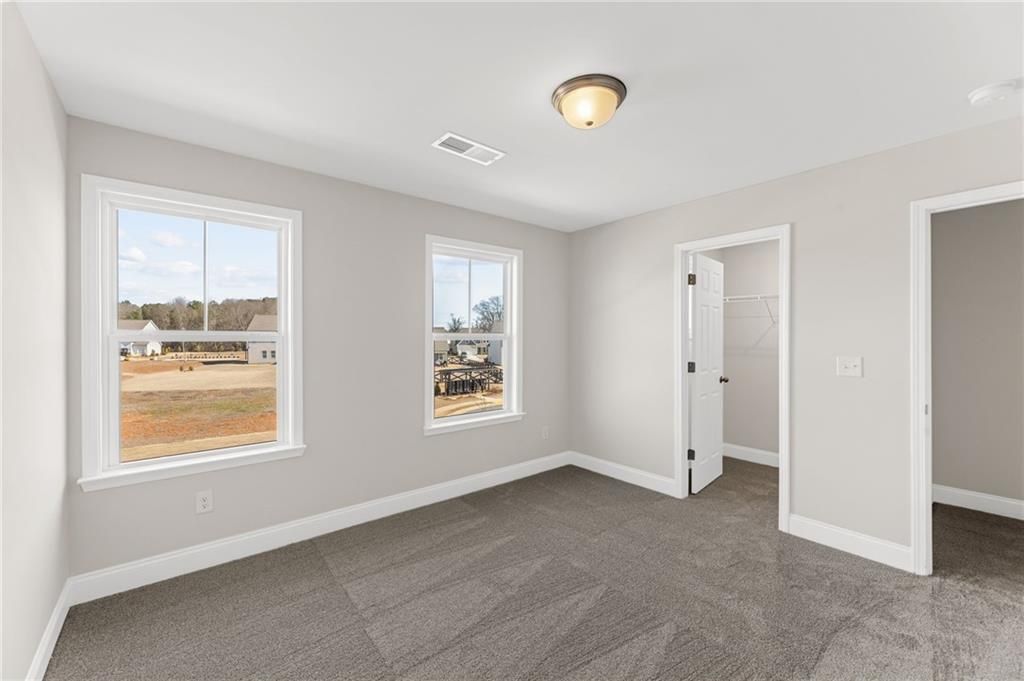 Bright secondary bedroom with large windows, gray walls, and carpet in Davidson Homes The Willow B, Hoschton, Georgia