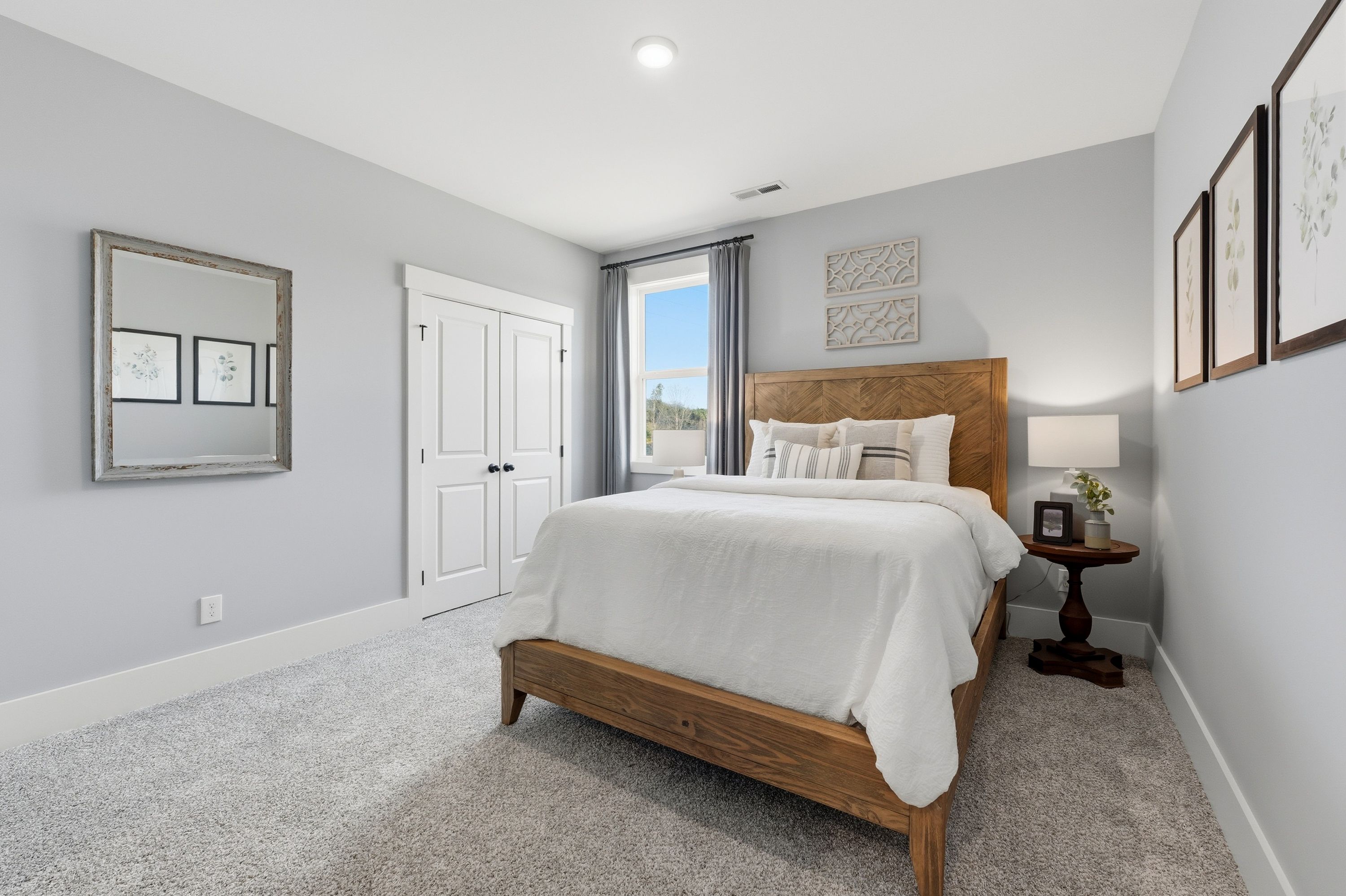 Spacious bedroom in Noble Ridge Cullman Alabama featuring wooden king bed white bedding gray walls and modern accents