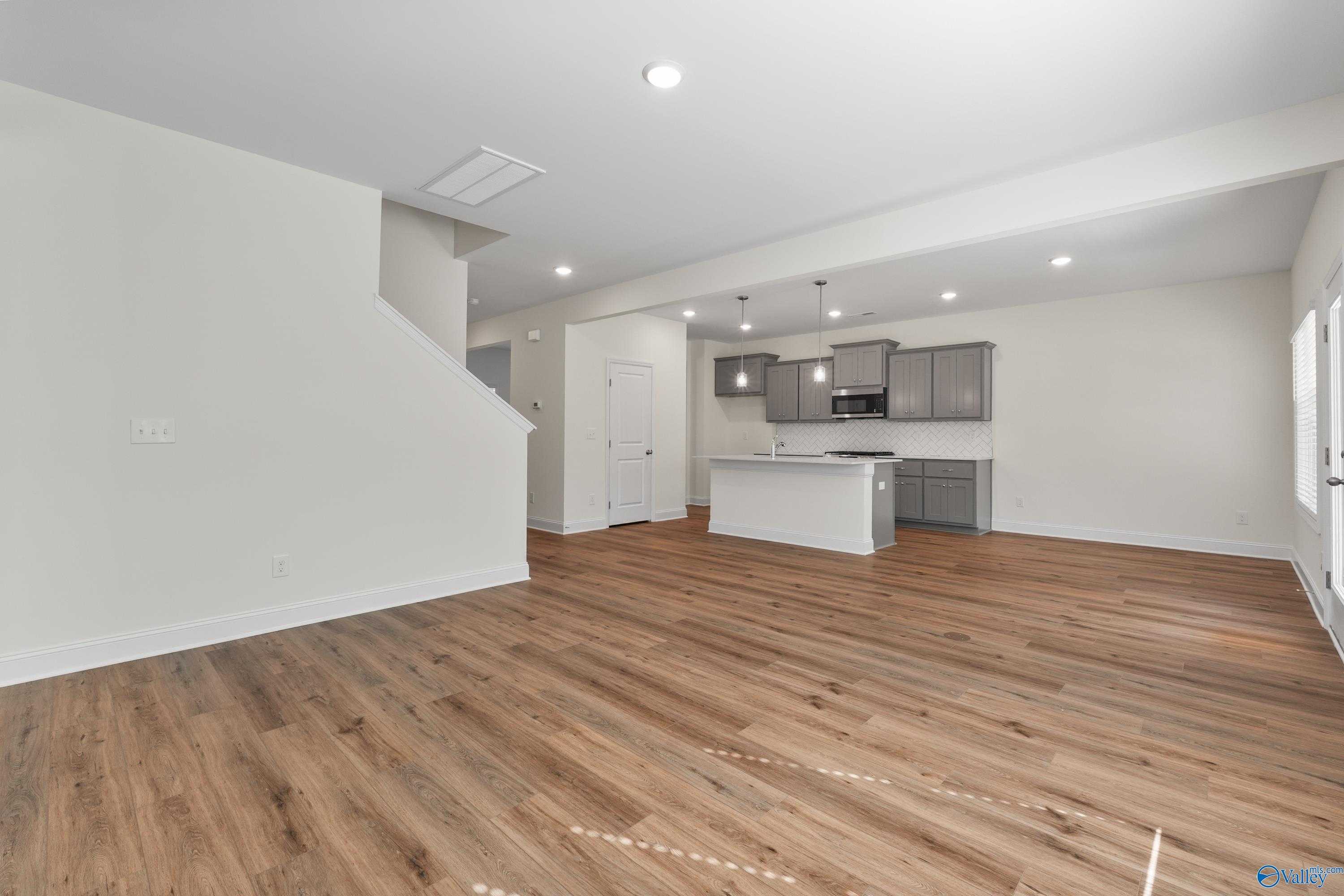 Modern open-concept kitchen with gray cabinets, white island, and hardwood floors in Davidson Homes The Shelby A, Athens, Alabama