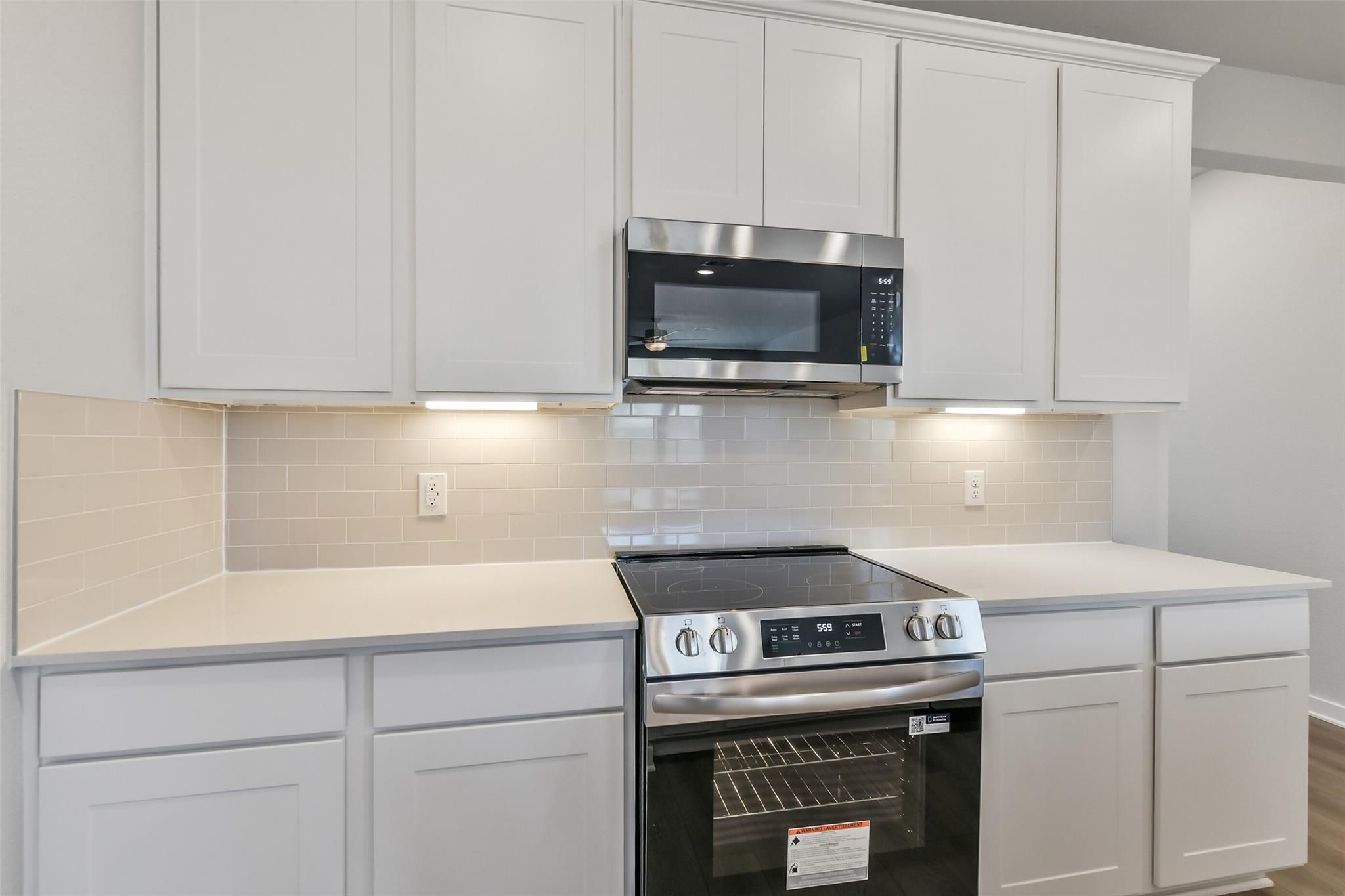 Modern white kitchen with shaker cabinets, quartz counters, stainless range, and subway tile backsplash in Davidson Homes The Colorado F, Cleveland TX