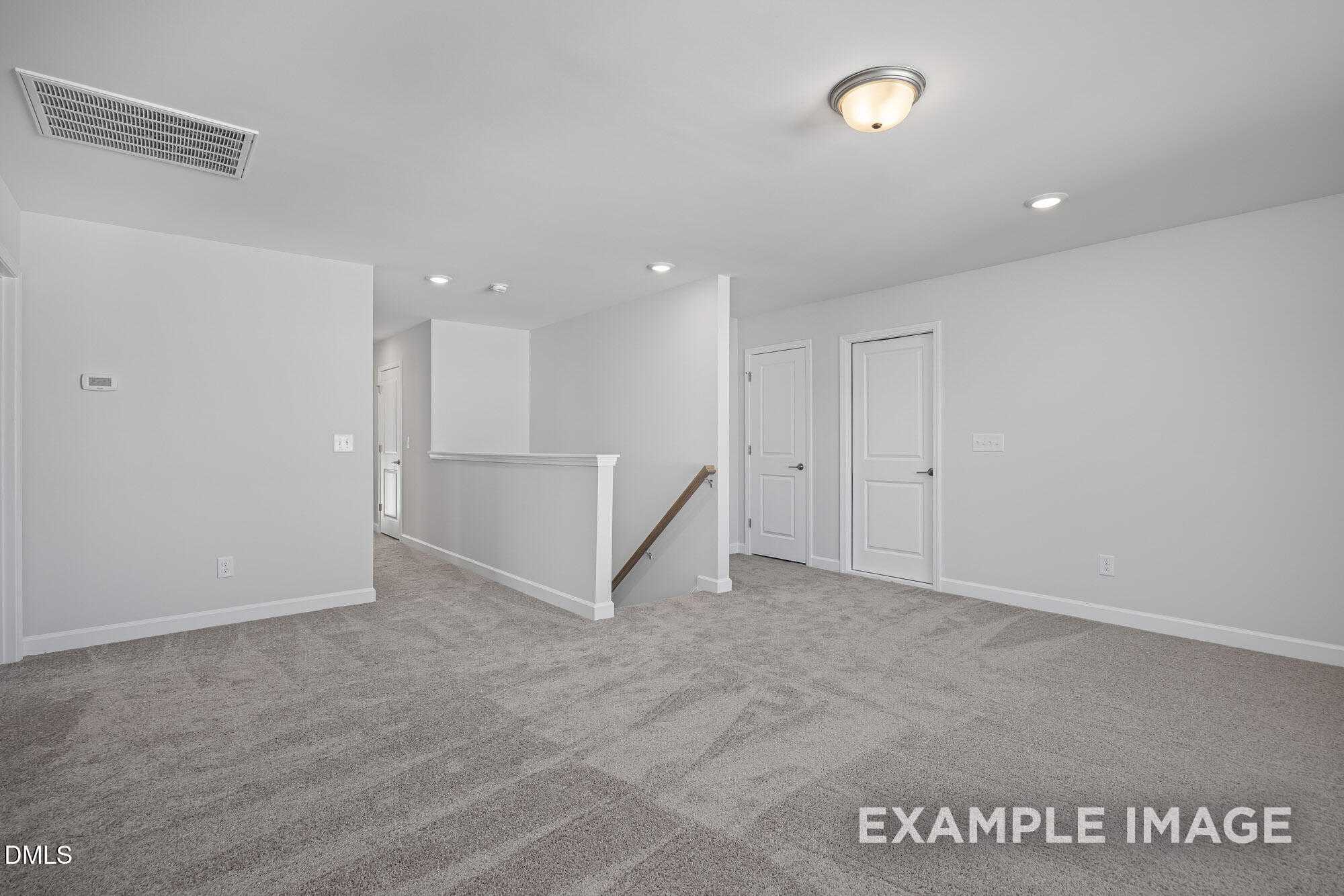Bright upstairs hallway with white walls, beige carpet, doors, and open stair railing in Davidson Homes The Cypress B II, Angier NC