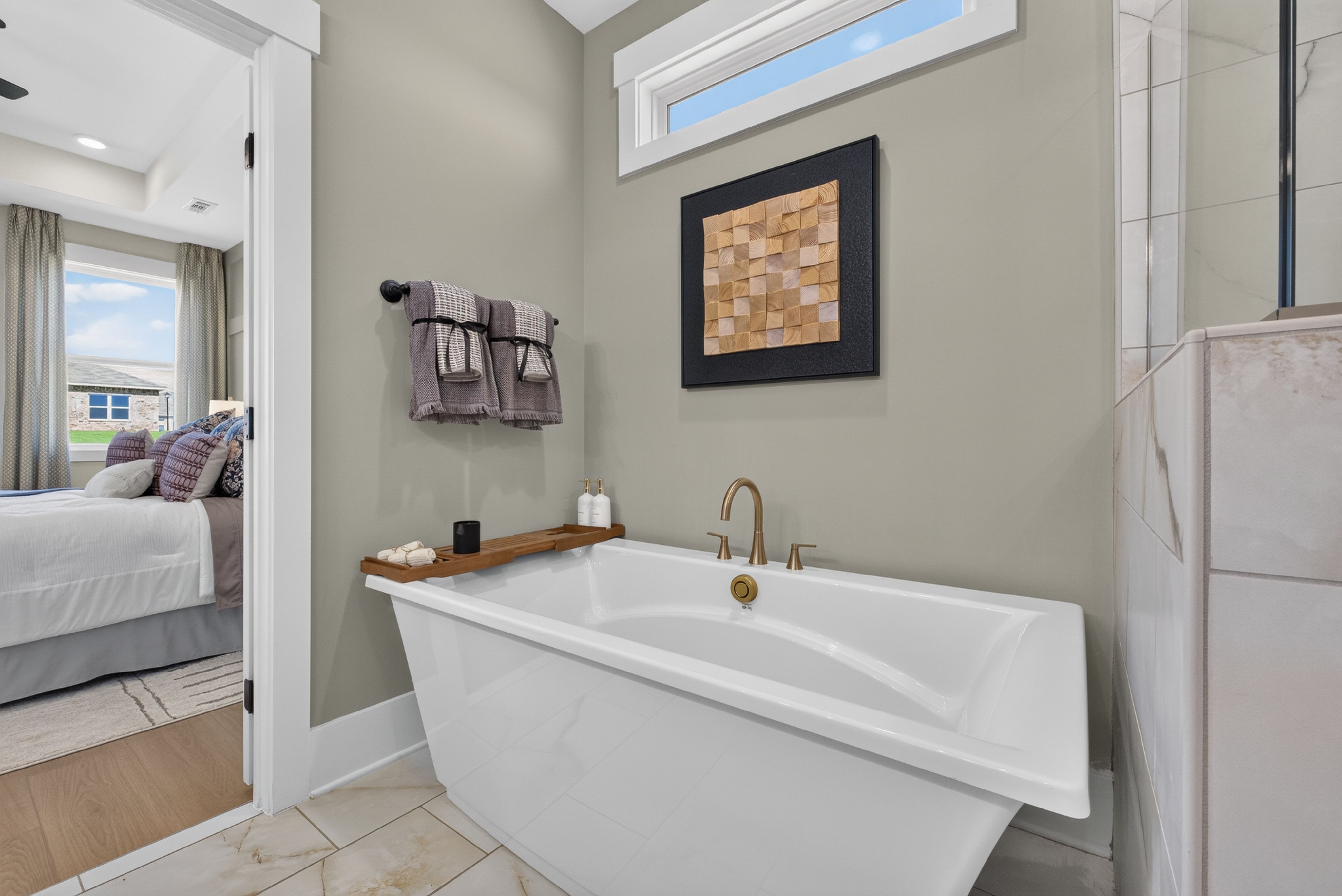 Freestanding soaking tub with brushed gold faucet in owner's bathroom at Evergreen Mill, Madison, Alabama by Davidson Homes