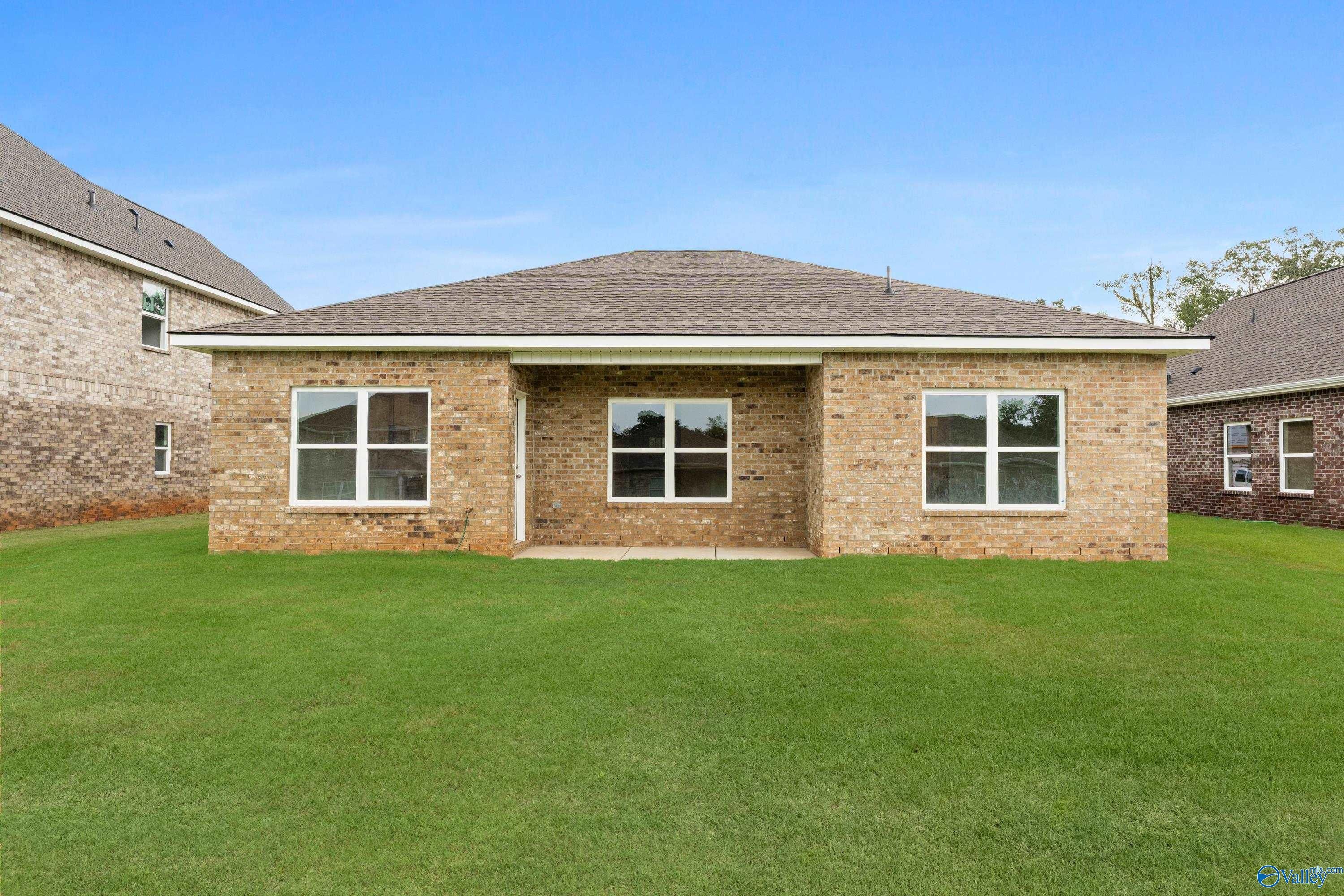 Single-story brick home facade with centered entry, large windows, lush green lawn and blue sky in Creek Grove, New Market, Alabama, Davidson Homes Asheville C
