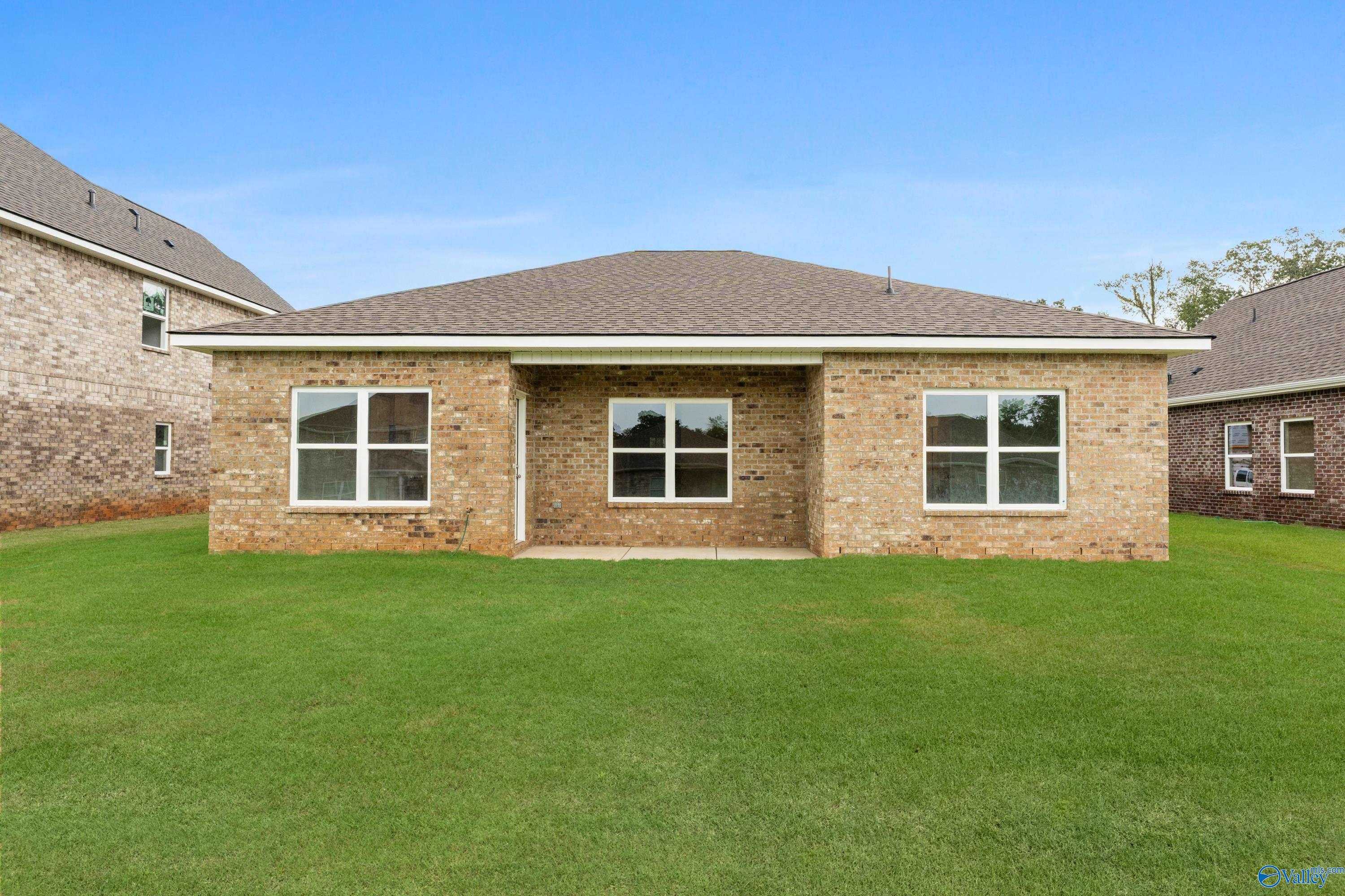 Single-story brick home facade with centered entry, large windows, lush green lawn and blue sky in Creek Grove, New Market, Alabama, Davidson Homes Asheville C