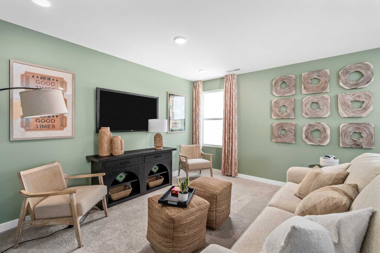 Cozy living room at Calista Farms in White House Tennessee with sage green walls, black media console, wicker chairs, and cream sofa
