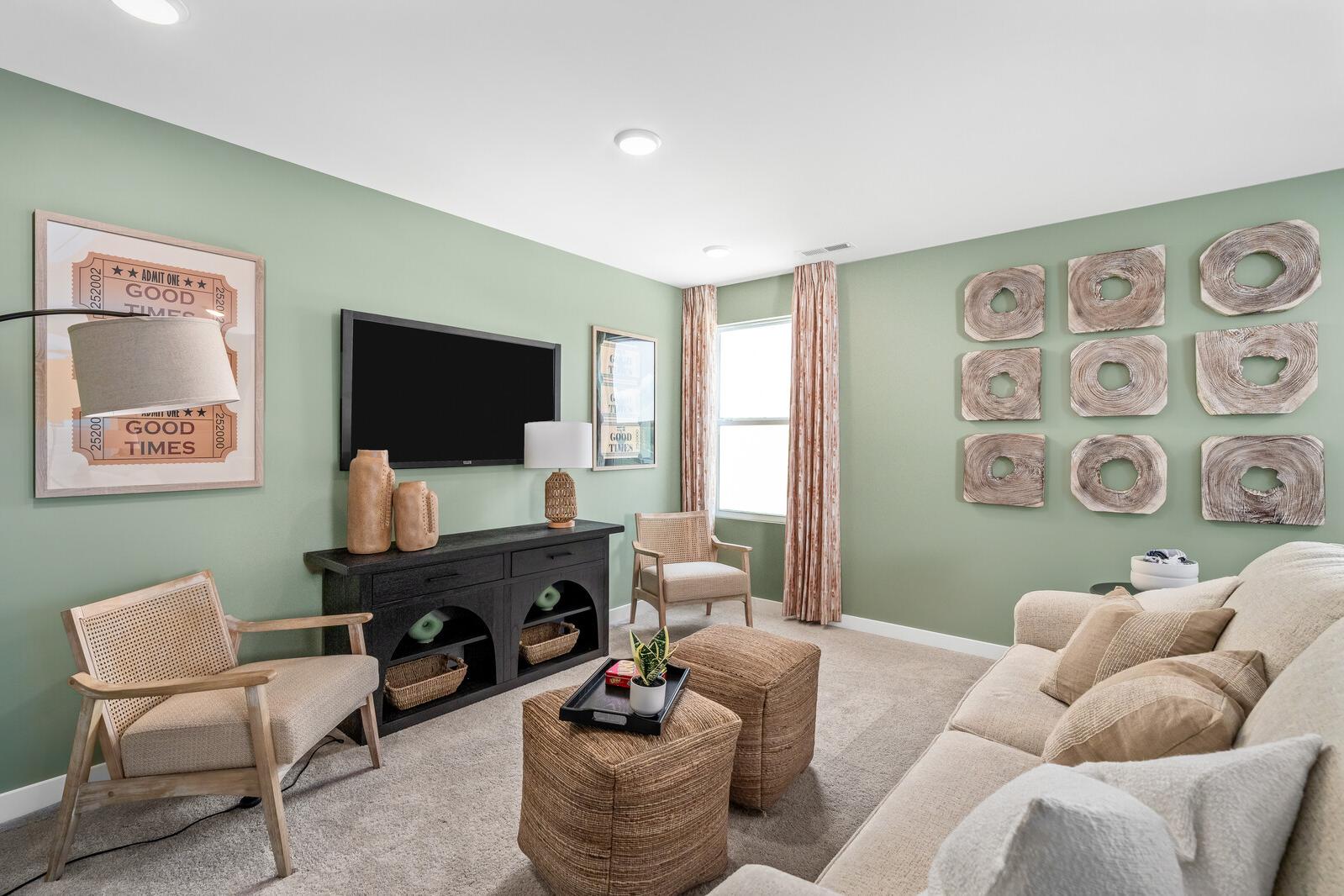 Cozy living room at Calista Farms in White House Tennessee with sage green walls, black media console, wicker chairs, and cream sofa