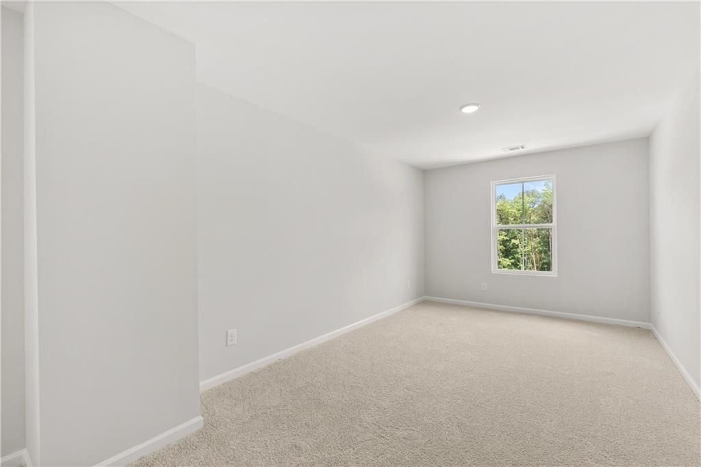 Bright, spacious secondary bedroom with plush carpeting in The Burton A floor plan at The Bluffs, Canton, Georgia.