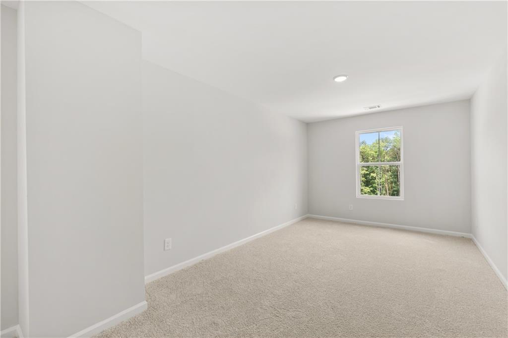 Bright, spacious secondary bedroom with plush carpeting in The Burton A floor plan at The Bluffs, Canton, Georgia.