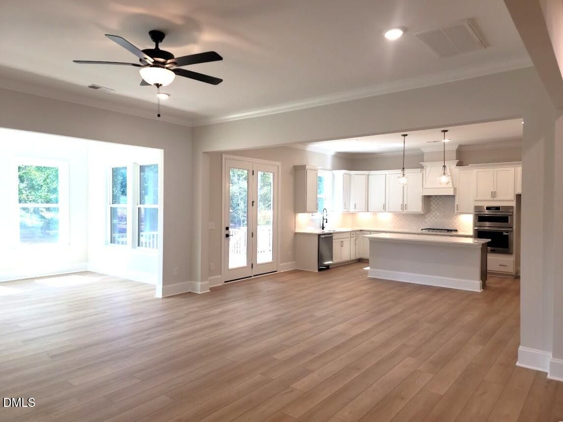 Open-concept living room and kitchen with white cabinetry, island, and hardwood floors in Davidson Homes Crawford D, Wake Forest NC