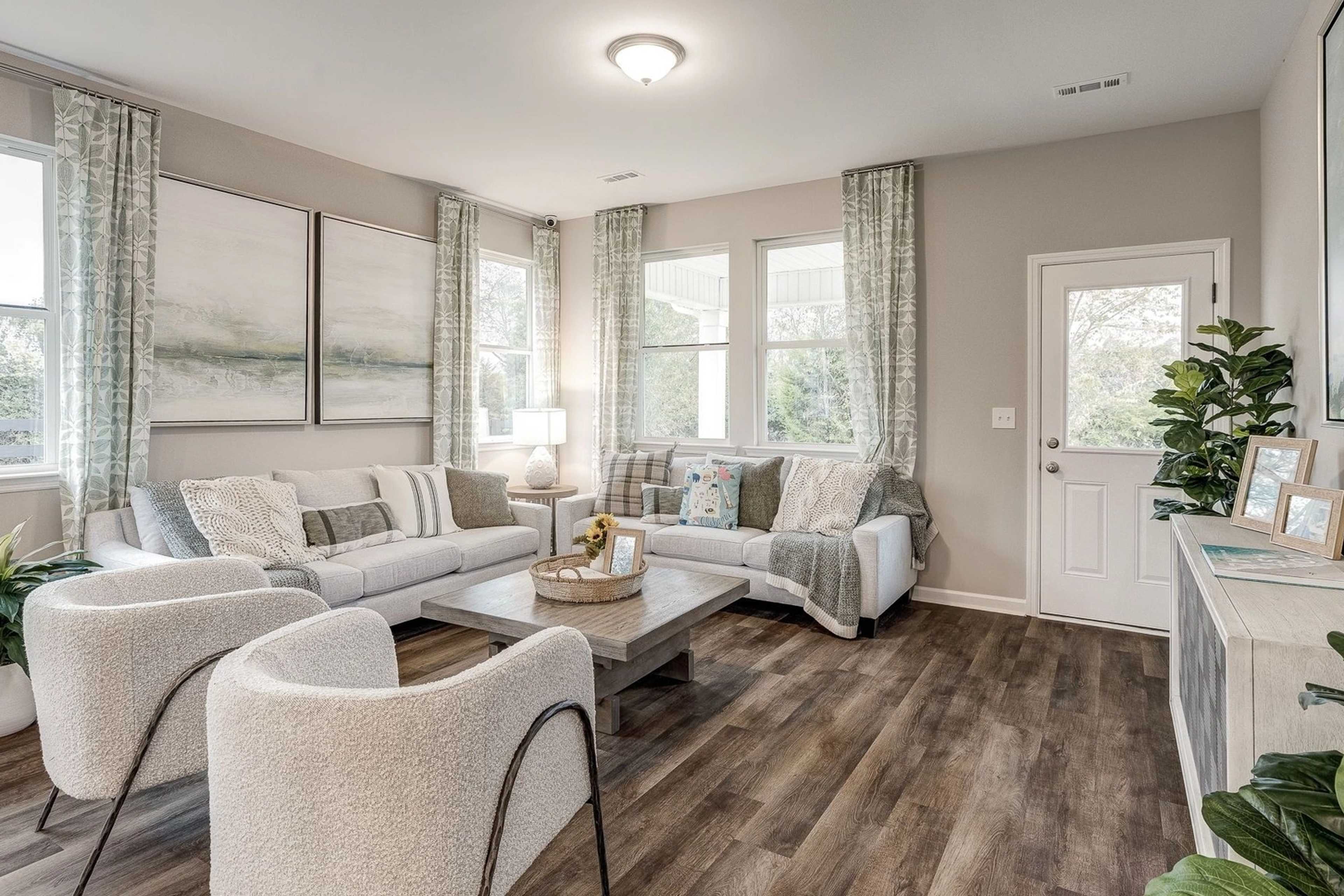 Cozy living room at Carroll Green in Harvest Alabama with white sectional sofa, armchairs, hardwood floors, potted plants