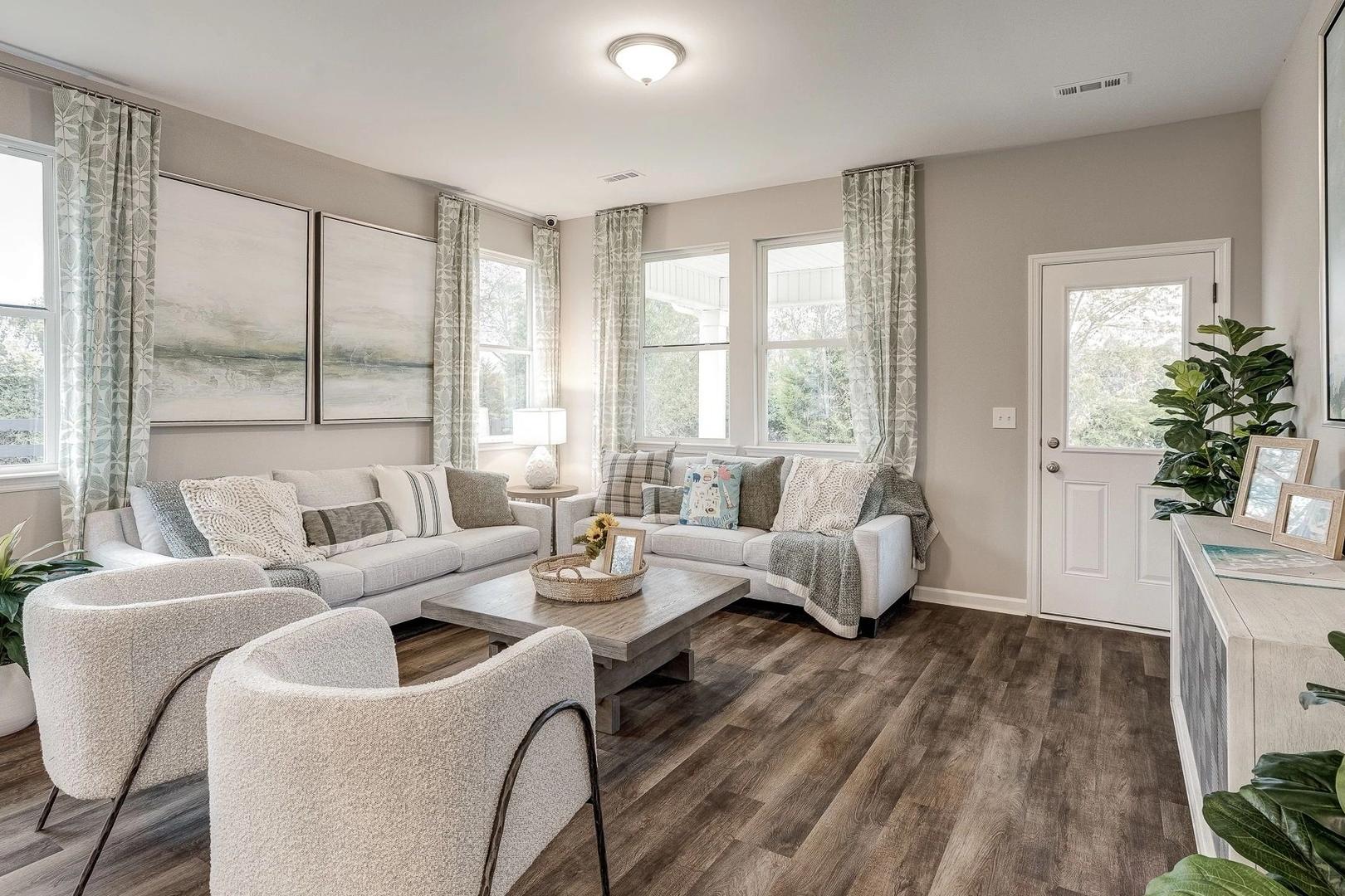 Cozy living room at Carroll Green in Harvest Alabama with white sectional sofa, armchairs, hardwood floors, potted plants