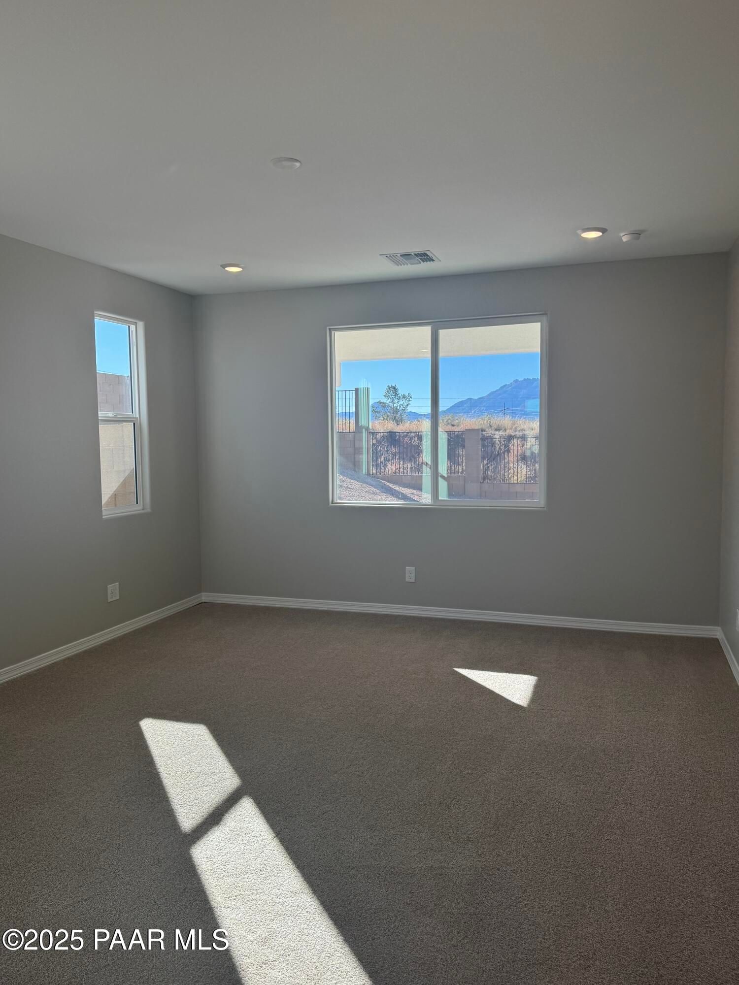 Sunlit empty room with gray walls, large windows overlooking desert mountains in 3-bedroom Davidson Homes The Monarch E, Prescott AZ