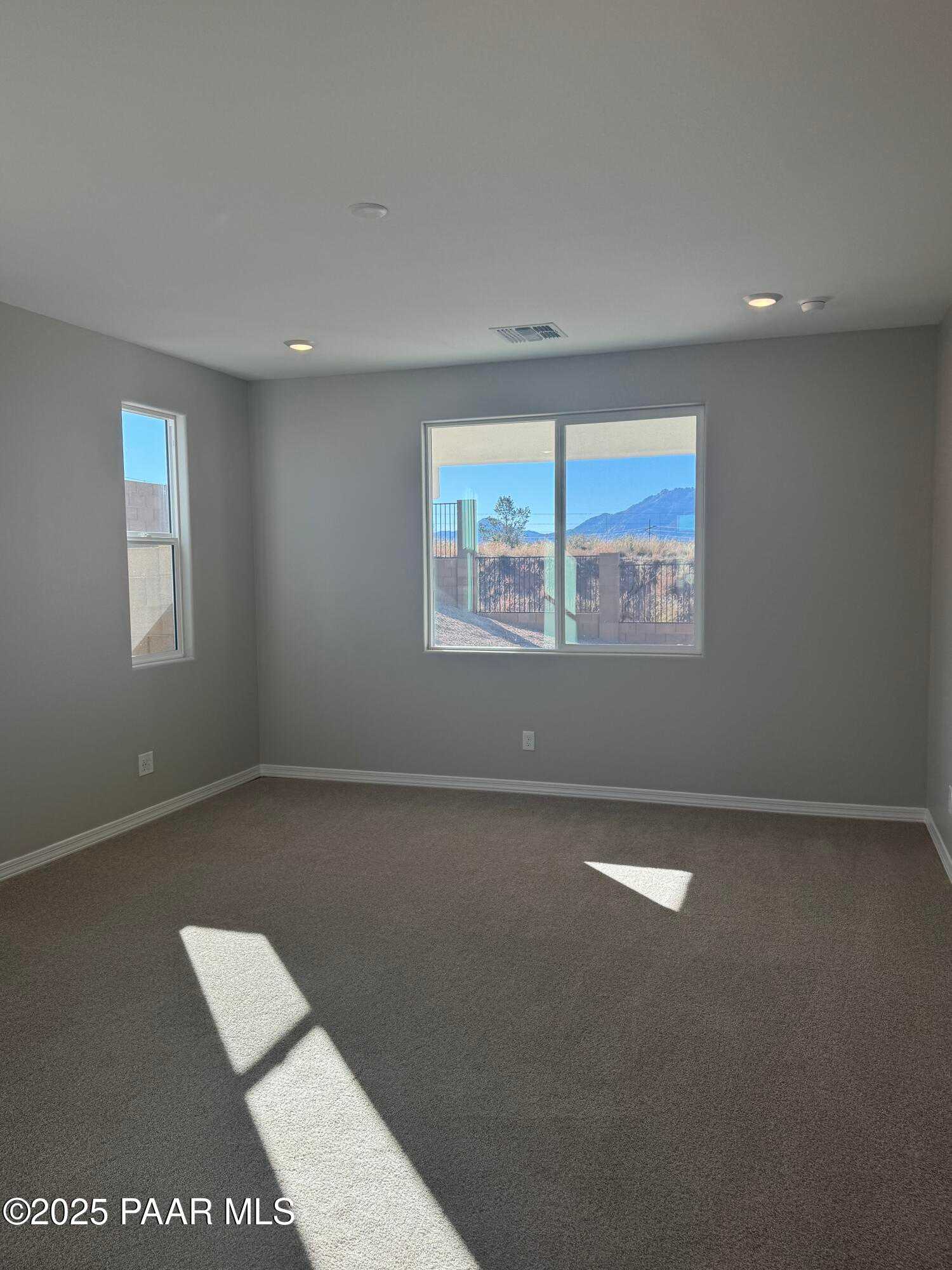 Sunlit empty room with gray walls, large windows overlooking desert mountains in 3-bedroom Davidson Homes The Monarch E, Prescott AZ