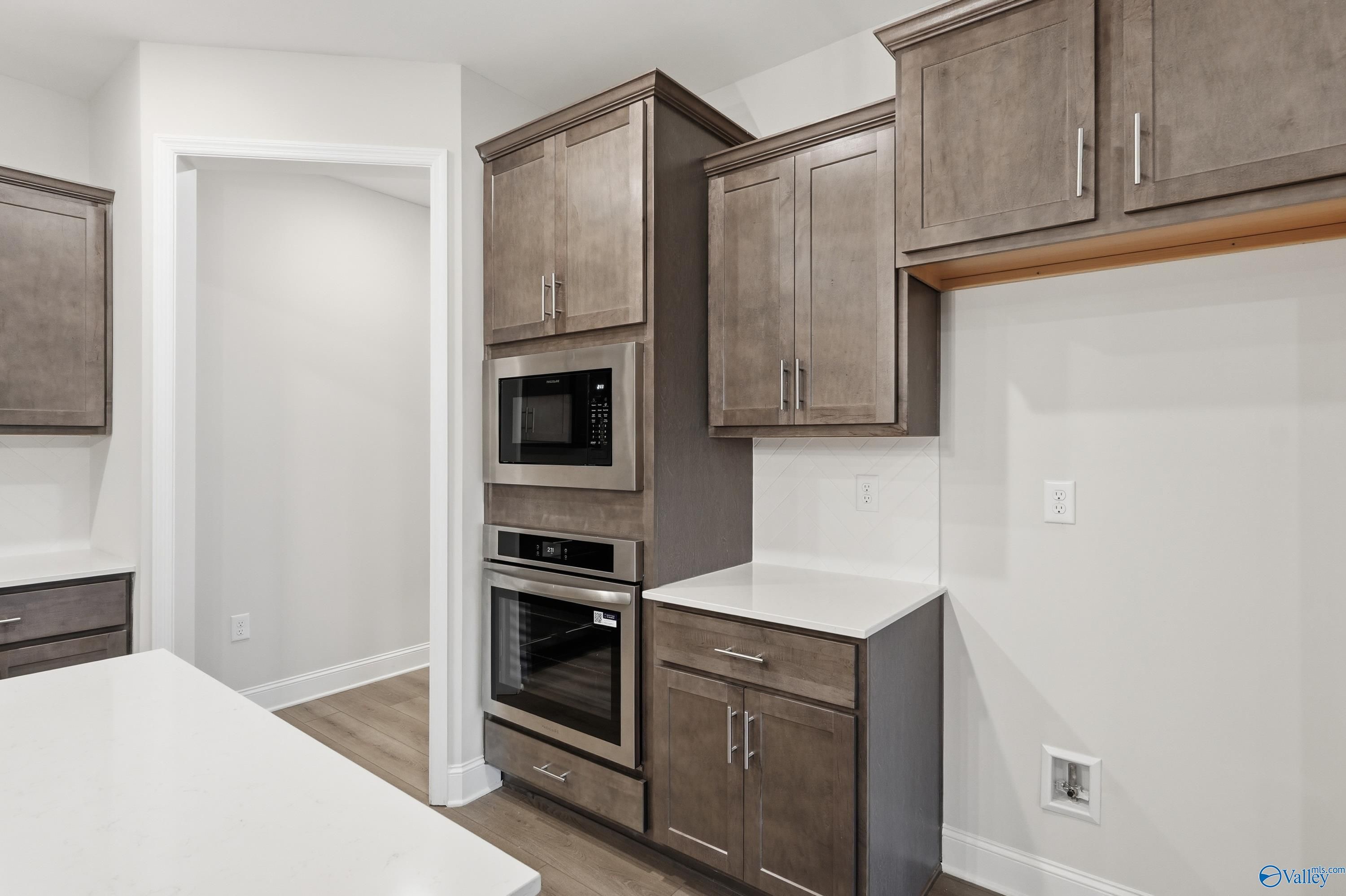 Modern kitchen featuring gray shaker cabinets, white quartz counters, and built-in double oven in Davidson Homes The Kirkland, Decatur, AL