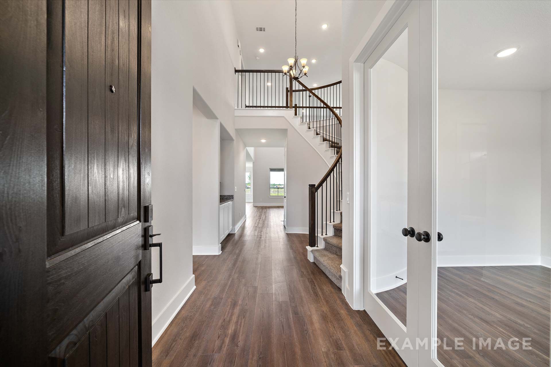 Foyer of The Victoria by Davidson Homes featuring curved staircase, dark wood door, and hardwood floors in Texas City, TX