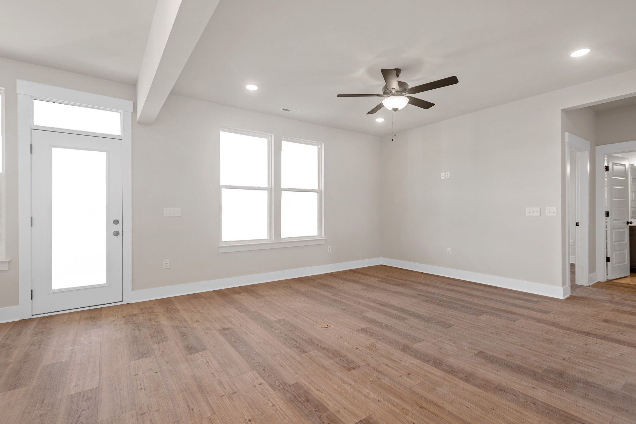 Bright living room with hardwood floors, ceiling fan, large windows, and French doors in Davidson Homes The Willow B, Calista Farms
