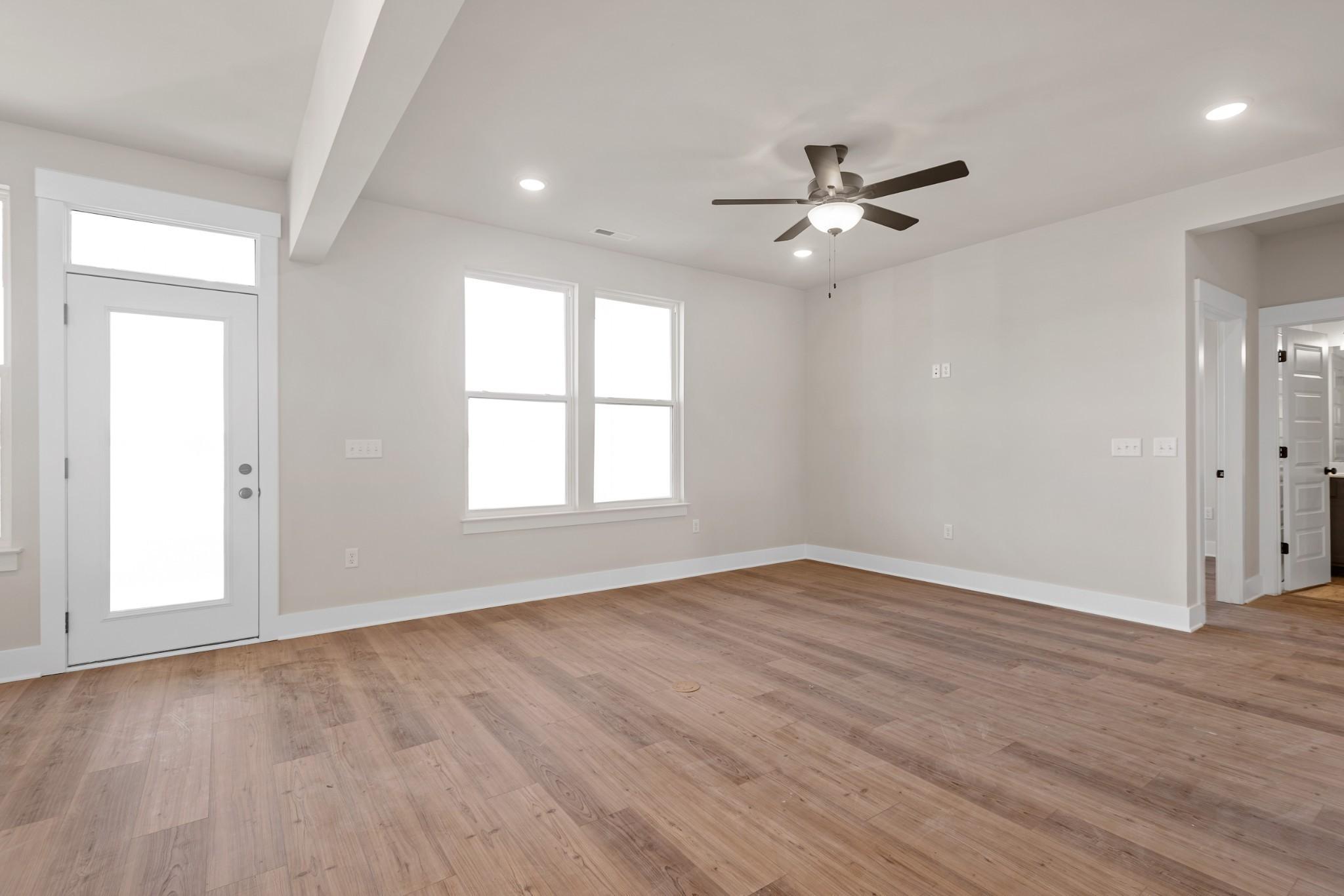 Bright living room with hardwood floors, ceiling fan, large windows, and French doors in Davidson Homes The Willow B, Calista Farms