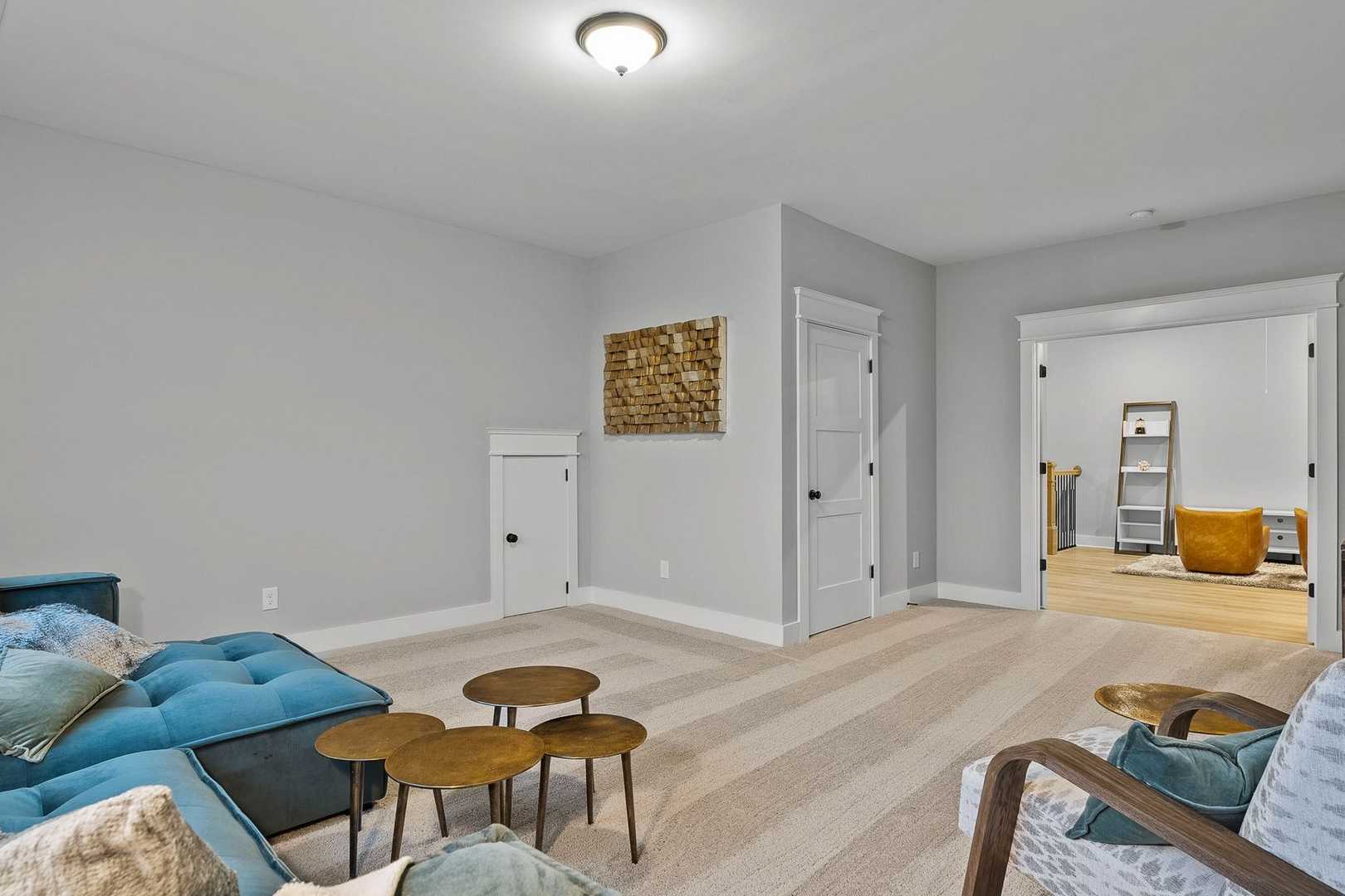 Cozy bonus room in The Oxford home with blue sectional sofa, woven wall art, and modern decor
