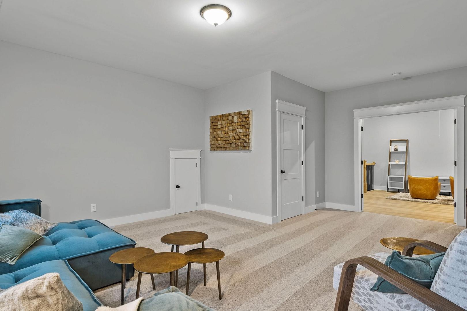 Cozy bonus room in The Oxford home with blue sectional sofa, woven wall art, and modern decor