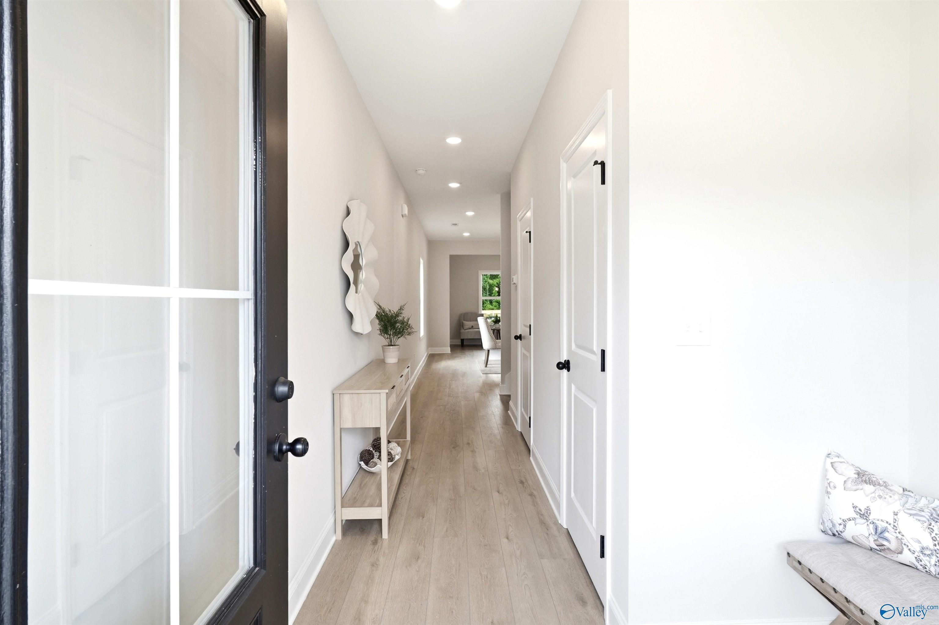 Bright entryway foyer with glass-panel front door, luxury vinyl plank flooring, and console table in Davidson Homes The Russell A, Huntsville