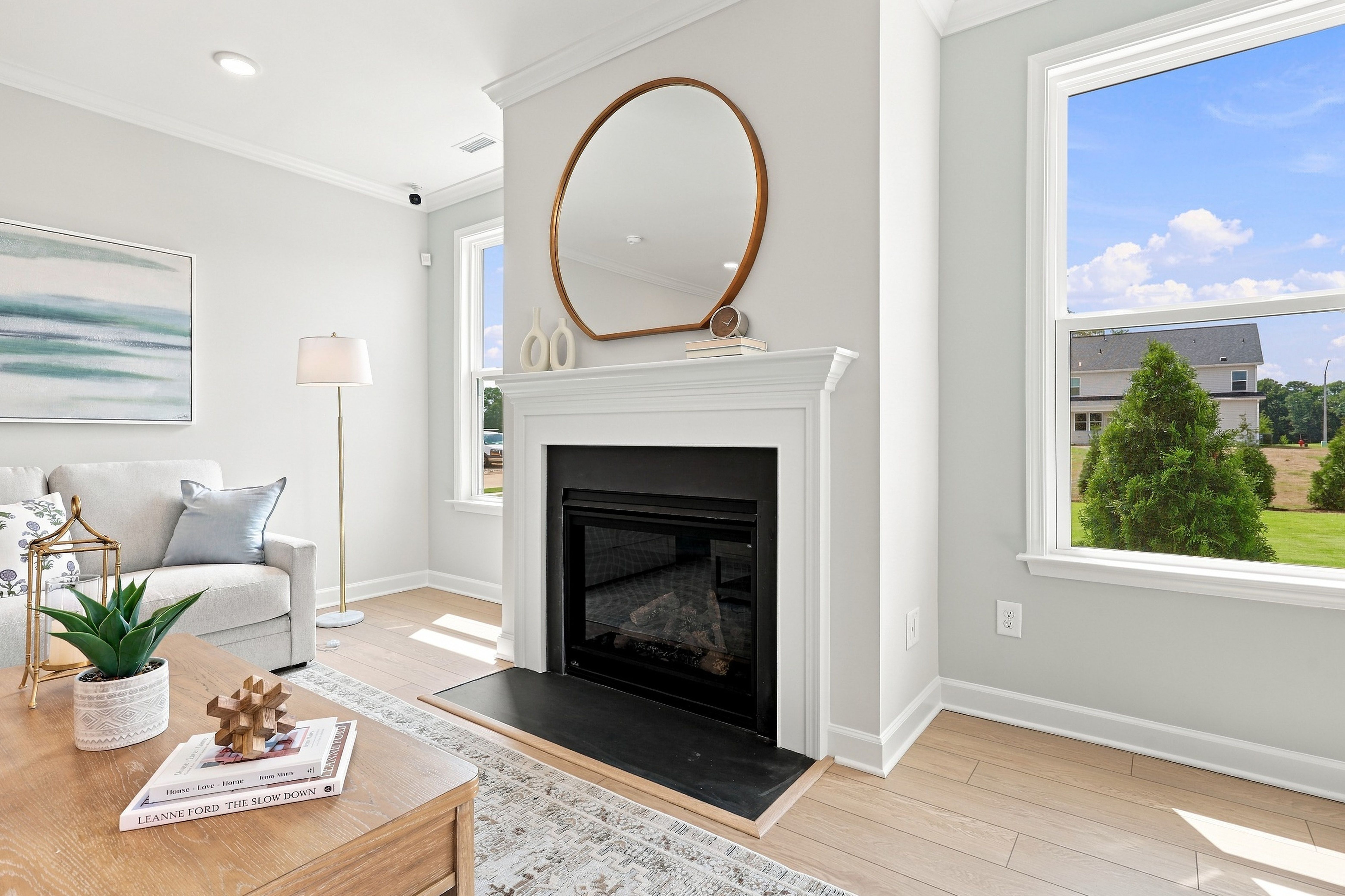 Bright living room in The Daphne D featuring a cozy fireplace, modern mantle decor, and hardwood floors.
