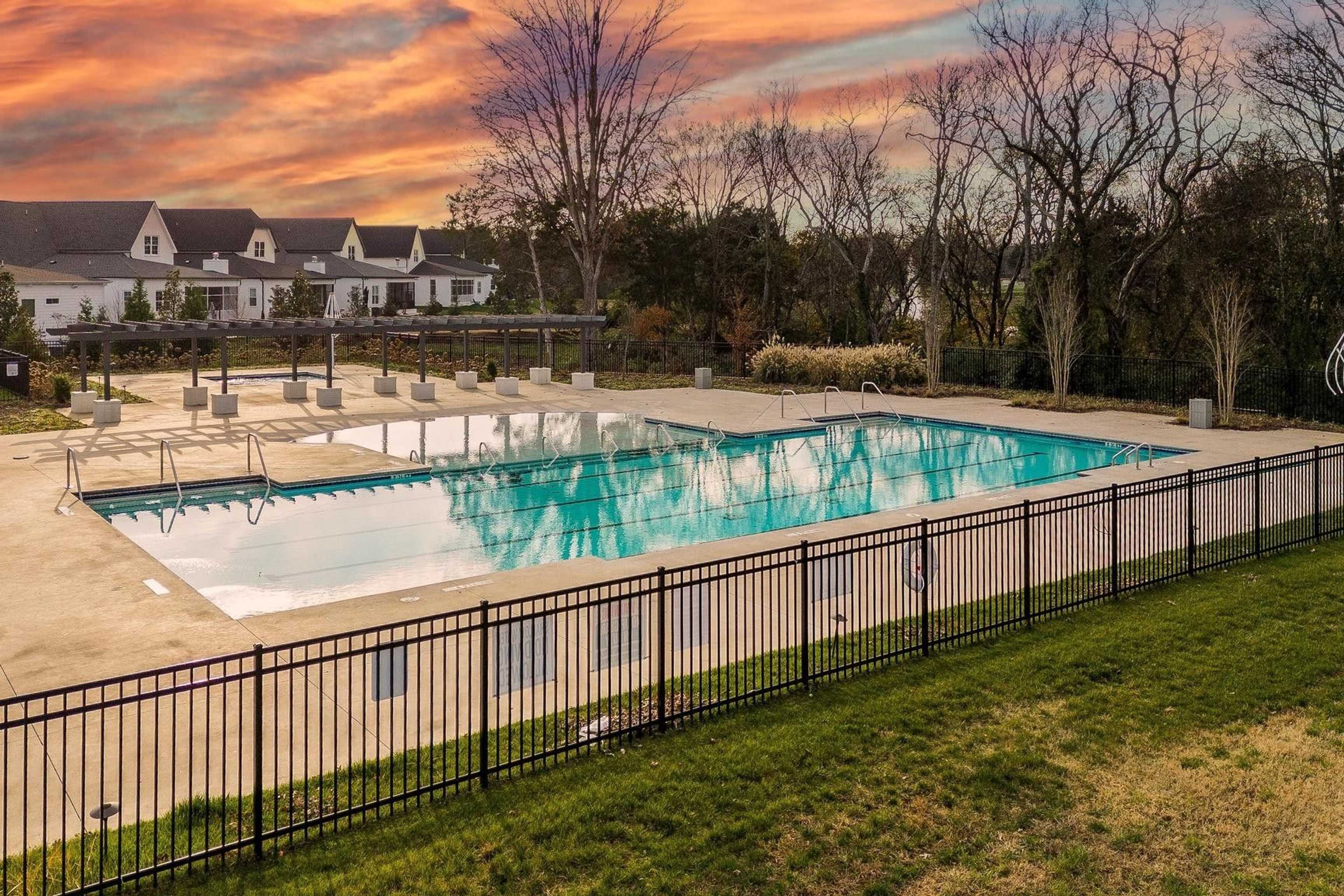 Resort-style community pool at Shelton Square in Murfreesboro Tennessee with lounge chairs umbrellas black fencing and sunset sky