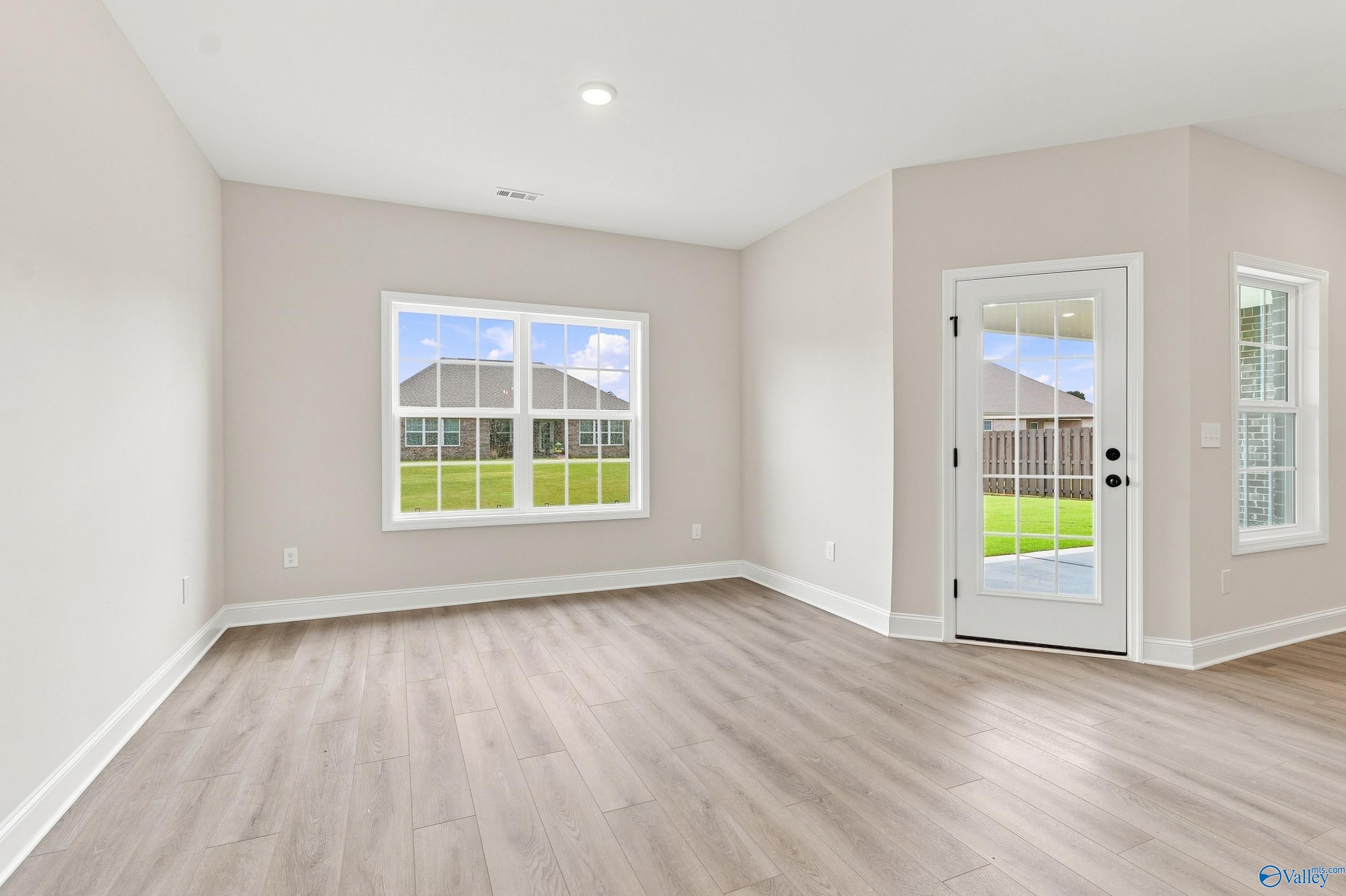 Bright living area with wood-look flooring and backyard access in The Rockford B floor plan, Kendall Downs, Toney, Alabama.