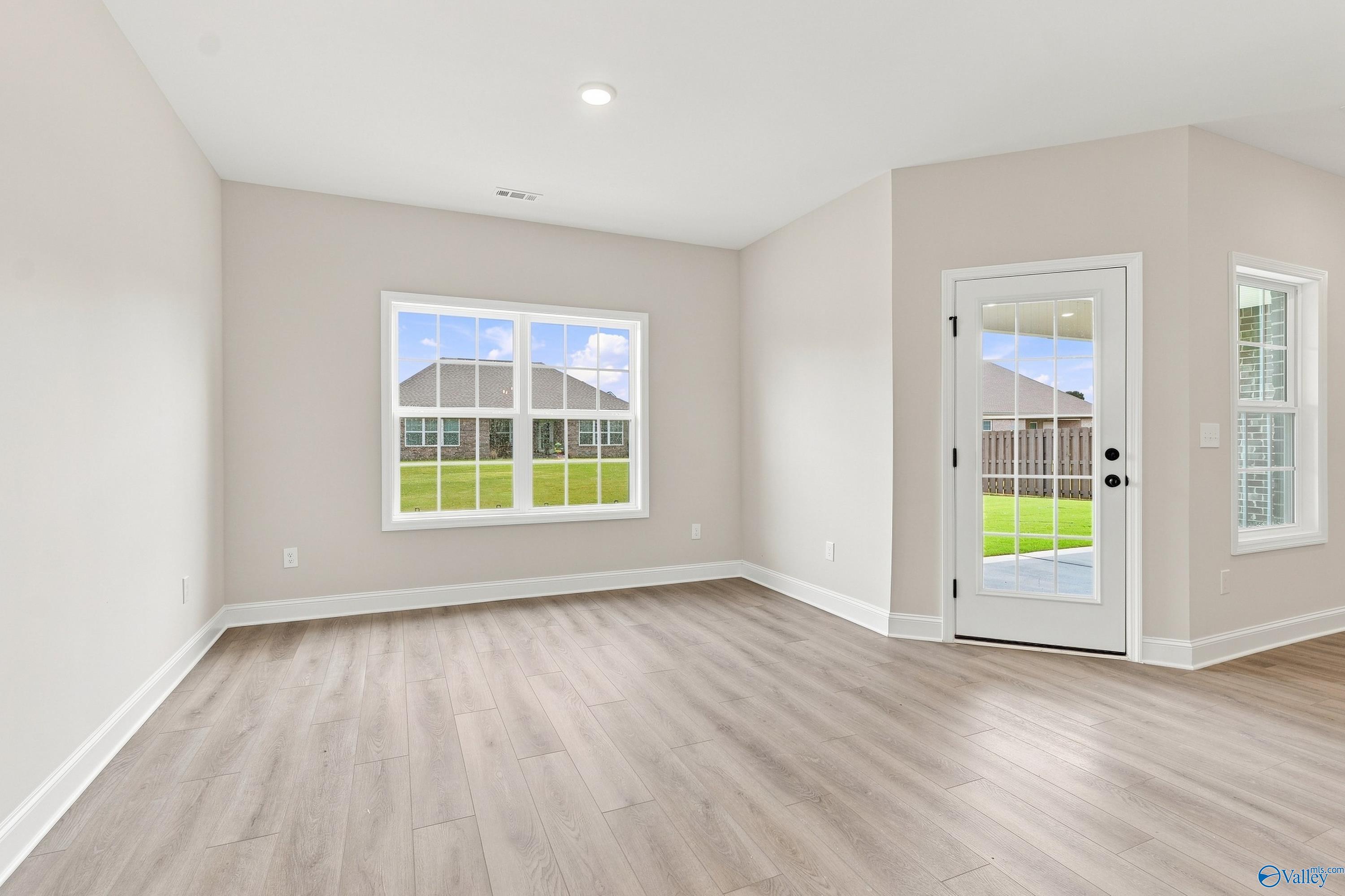 Bright living area with wood-look flooring and backyard access in The Rockford B floor plan, Kendall Downs, Toney, Alabama.
