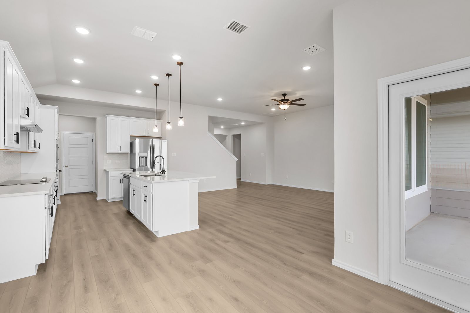 Open-concept kitchen and living area in The Sequoia C featuring white cabinetry, a center island, and wood-style flooring.